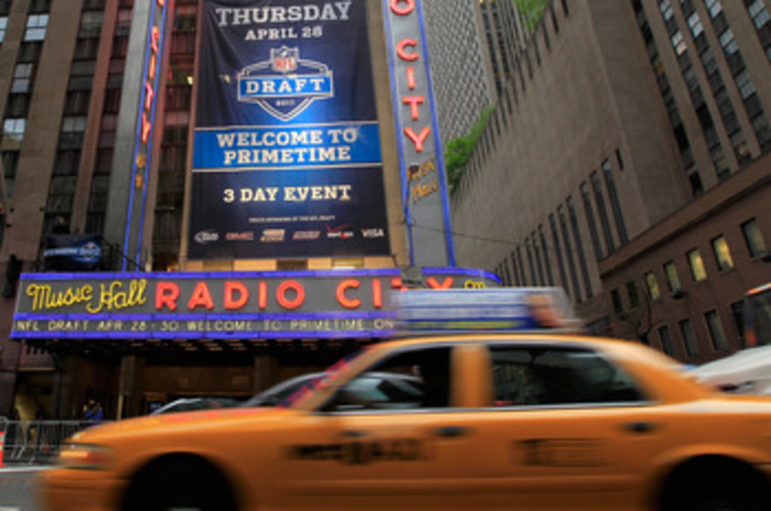 NEW YORK, NY - APRIL 28:  Taxi cabs drive down the Avenue of the Americas past the Radio City Music Hall marquee, site of the 2011 NFL Draft, on April 28, 2011 in New York City.  (Photo by Chris Trotman/Getty Images)