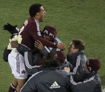 COMMERCE CITY, CO - APRIL 30:  Andre Akpan #19 of the Colorado Rapids leaps into the arms of his teammates on the bench as he celebrates his equalizing goal in the 49th minute against the Chicago Fire at Dick's Sporting Goods Park on April 30, 2011 in Com