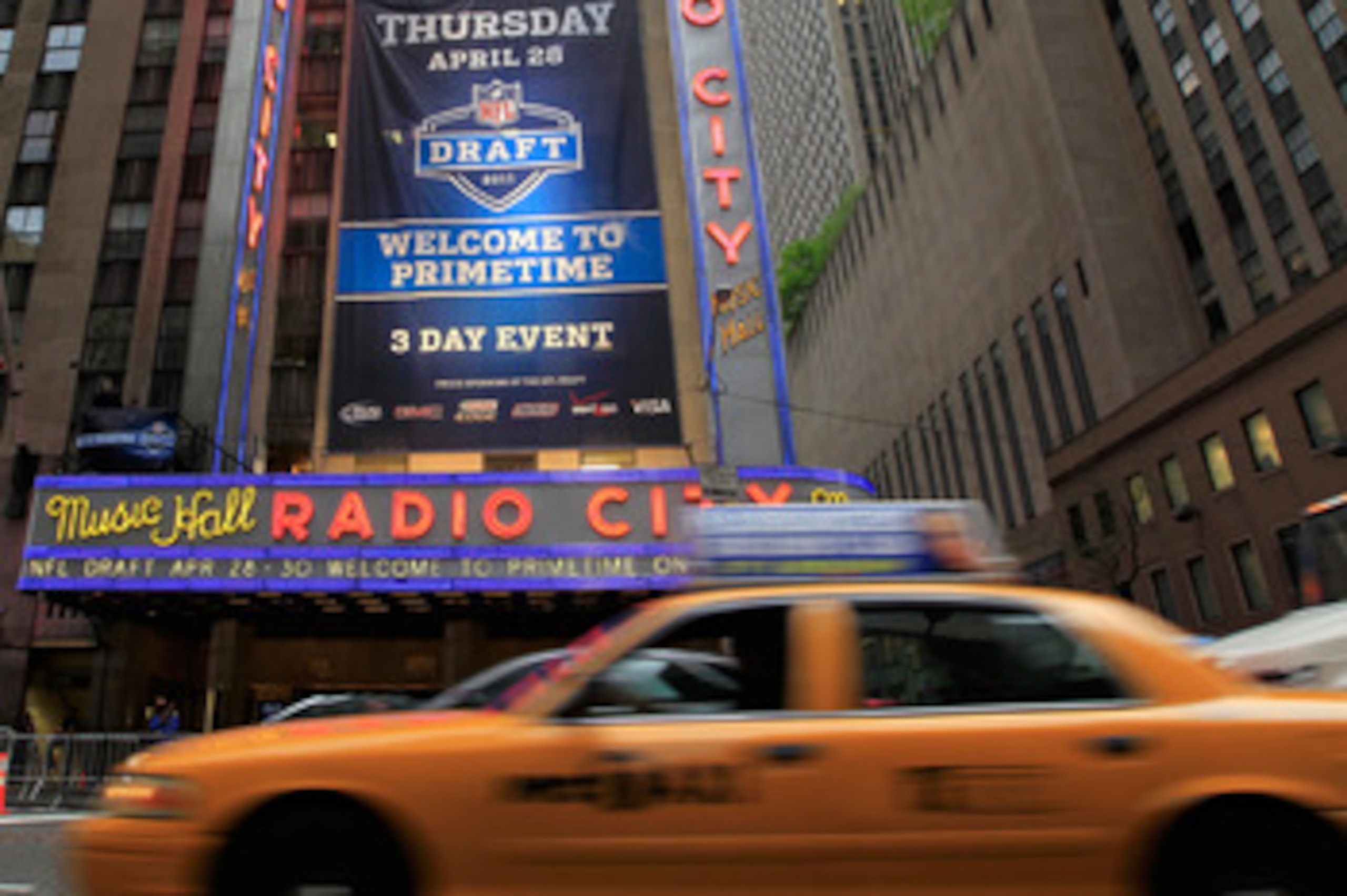 NEW YORK, NY - APRIL 28:  Taxi cabs drive down the Avenue of the Americas past the Radio City Music Hall marquee, site of the 2011 NFL Draft, on April 28, 2011 in New York City.  (Photo by Chris Trotman/Getty Images)