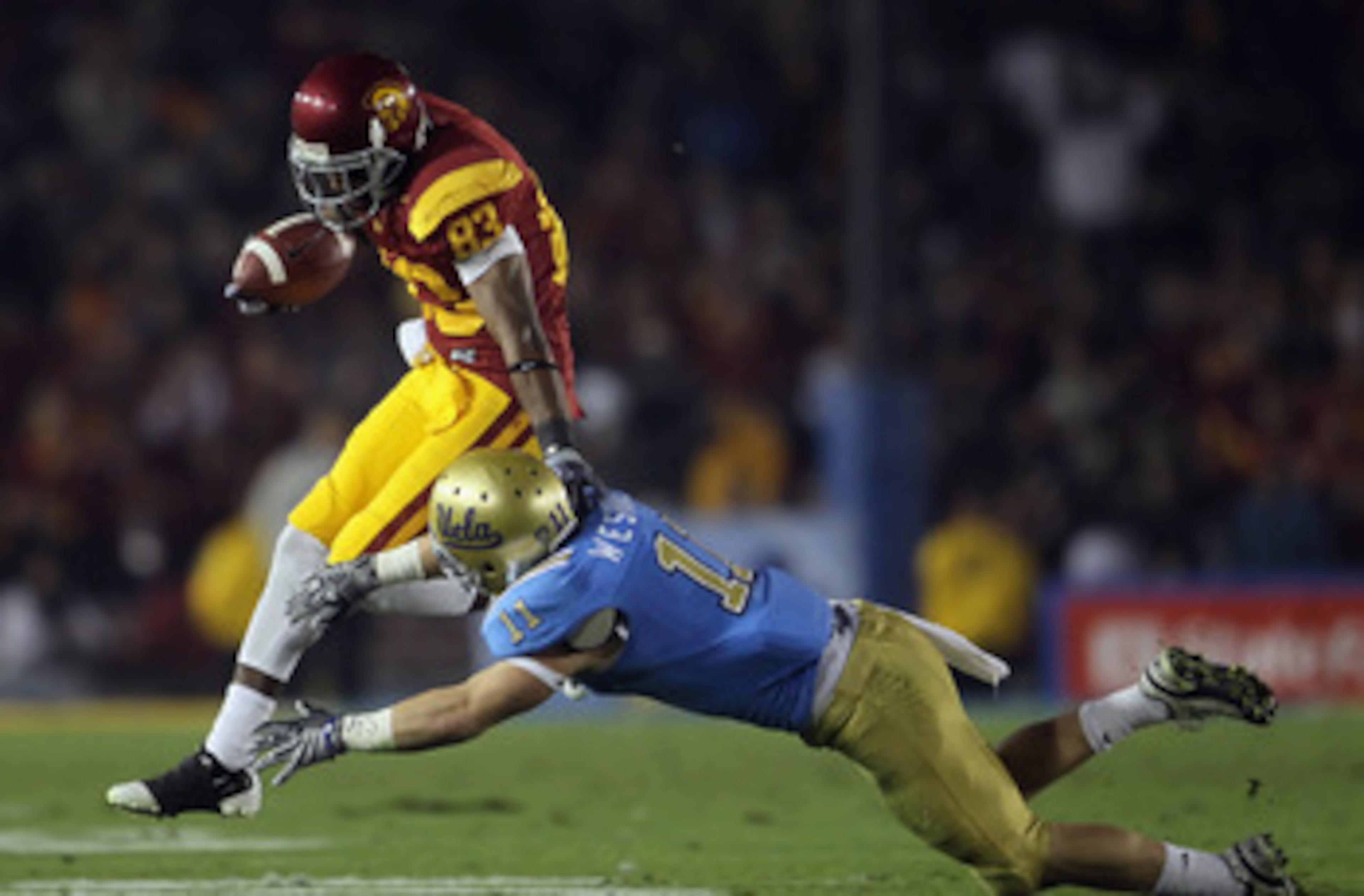 PASADENA, CA - DECEMBER 04:  Wide receiver Ronald Johnson #83 of the USC Trojans breaks a tackle by Sean Westgate #11 of the UCLA Bruins during the first half at the Rose Bowl on December 4, 2010 in Pasadena, California. USC defeated UCLA 28-14.  (Photo b