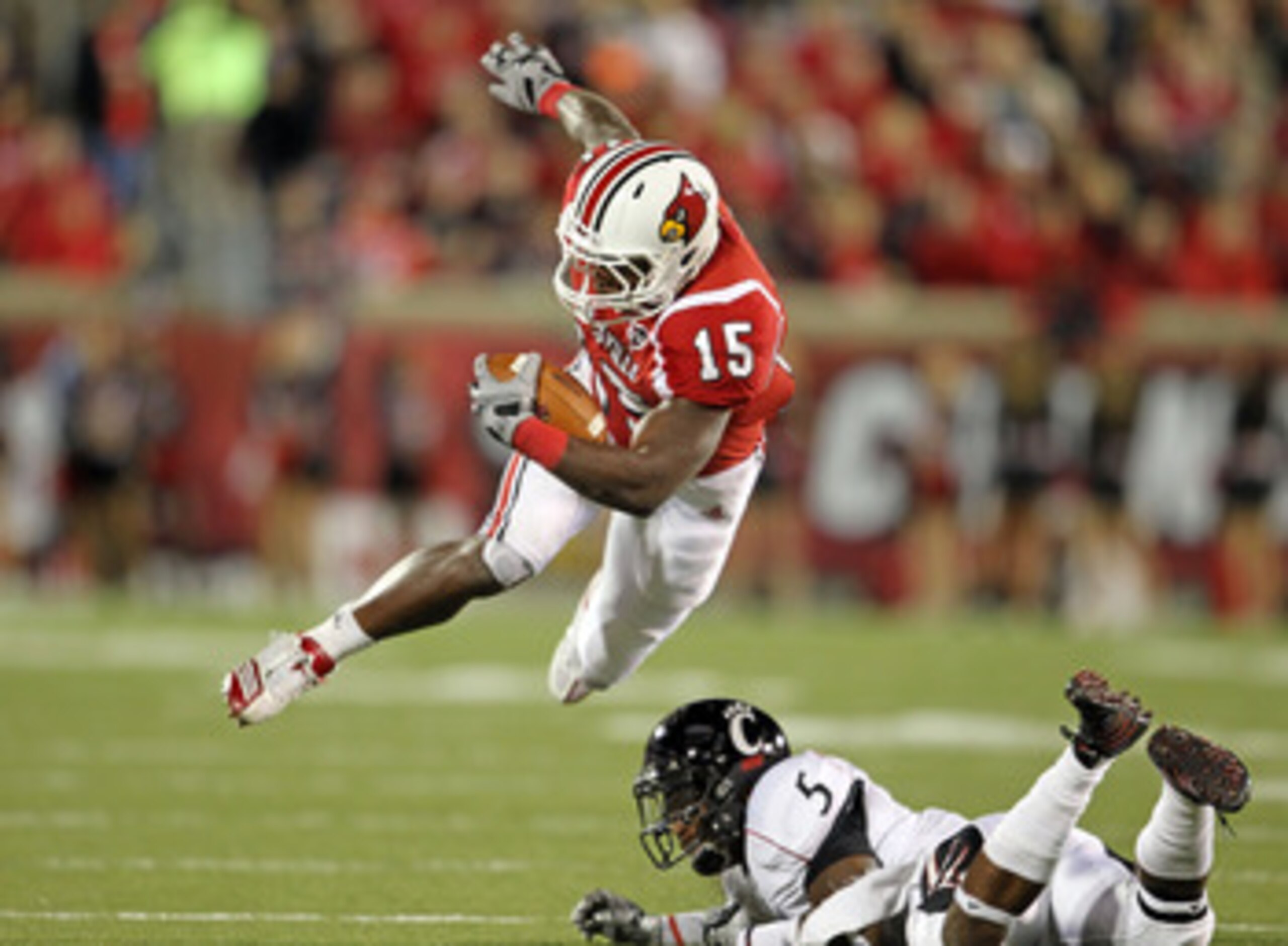 LOUISVILLE, KY - OCTOBER 15:  Bilal Powell #15 of  the Louisville Cardinals runs with the ball while tackled by Reuben Johnson #5 of the Cincinnati Bearcats during the game at Papa John's Cardinal Stadium on October 15, 2010 in Louisville, Kentucky.  (Pho