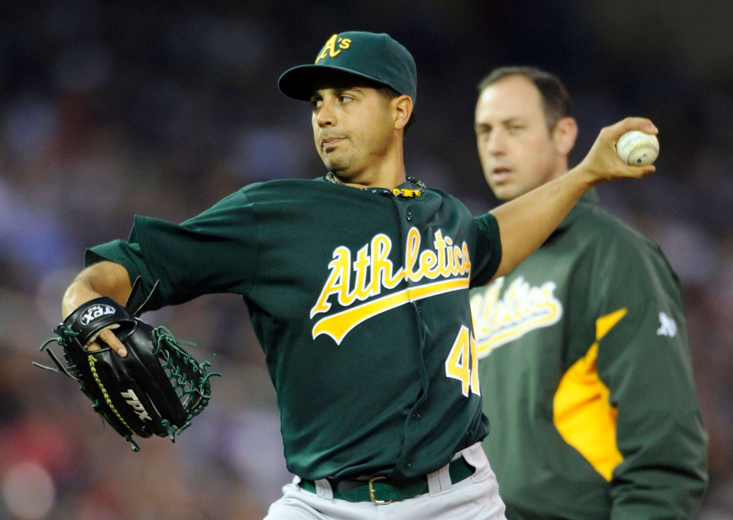 MINNEAPOLIS, MN - APRIL 9: Starting pitcher Gio Gonzalez #47 of the Oakland Athletics throws while athletic trainer Nick Paparesta looks on during the fifth inning of their game on April 9, 2011 at Target Field in Minneapolis, Minnesota. Athletics defeate