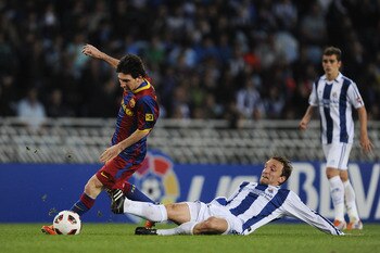 SAN SEBASTIAN, SPAIN - APRIL 30:  Lionel Messi of FC Barcelona (L) fights for the ball against Diego Rivas of Real Sociedad during the La Liga match between Real Sociedad and Barcelona at Estadio Anoeta on April 30, 2011 in San Sebastian, Spain. Real Soci
