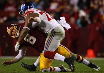 LANDOVER, MD - JANUARY 02:  Quarterback Rex Grossman #5 of the Washington Redskins is hit by defensive end Osi Umenyiora #72 of the New York Giants at FedEx Field on January 2, 2011 in Landover, Maryland. The Giants won the game 17-14.  (Photo by Win McNa