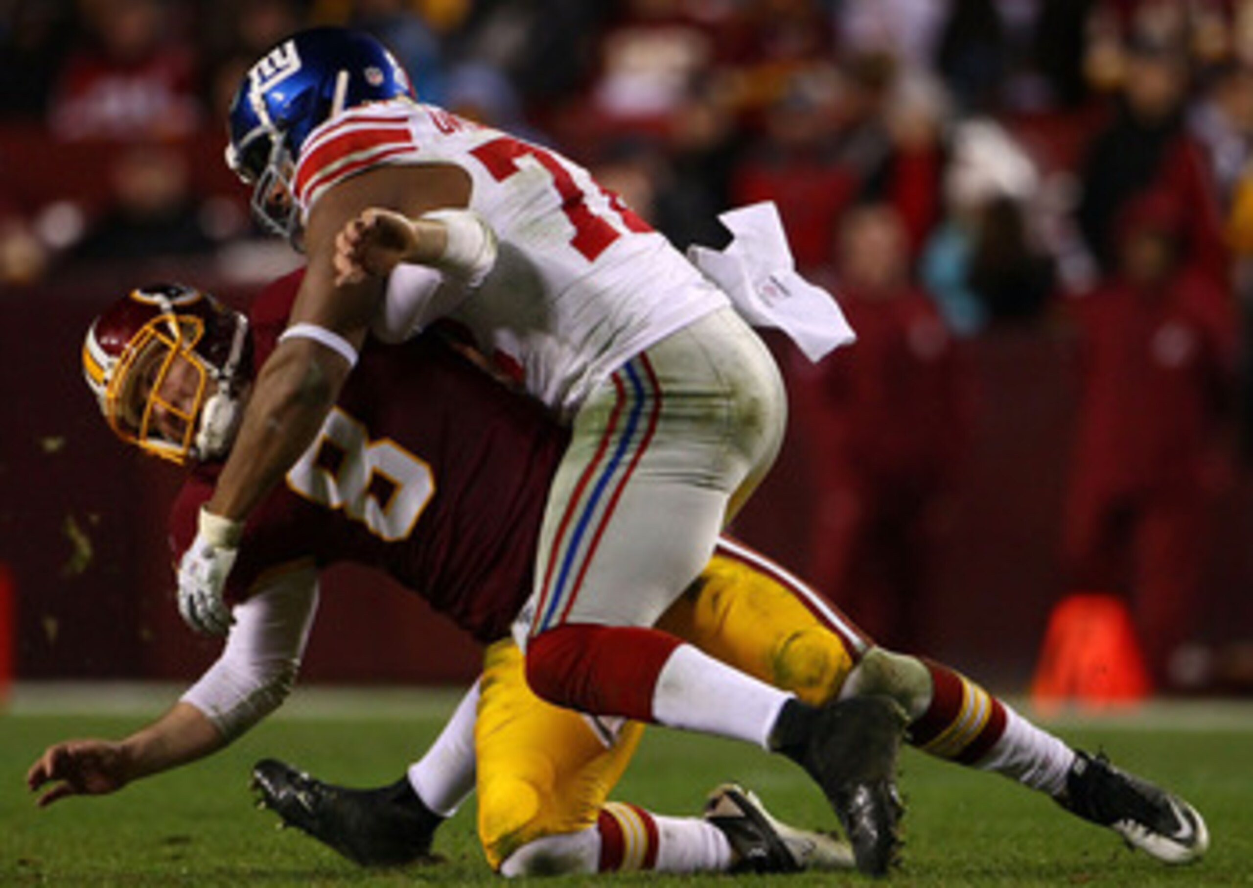 LANDOVER, MD - JANUARY 02:  Quarterback Rex Grossman #5 of the Washington Redskins is hit by defensive end Osi Umenyiora #72 of the New York Giants at FedEx Field on January 2, 2011 in Landover, Maryland. The Giants won the game 17-14.  (Photo by Win McNa