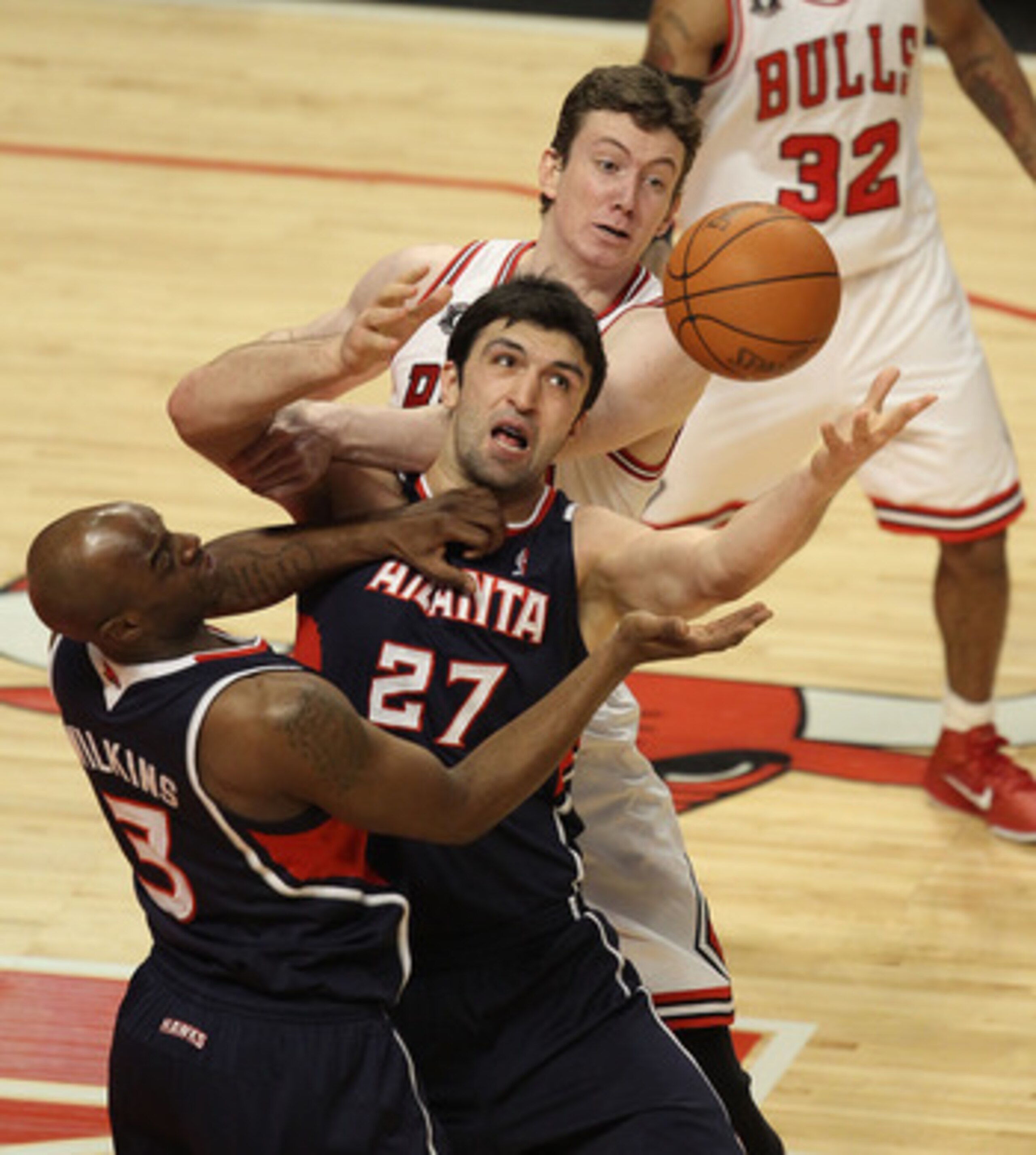 CHICAGO, IL - MARCH 11: Zaza Pachulia #27 and Damien Wilkins #3 of the Atlanta Hawks try to control the ball in front of Omer Asik #3 of the Chicago Bulls at the United Center on March 11, 2011 in Chicago, Illinois. NOTE TO USER: User expressly acknowledg