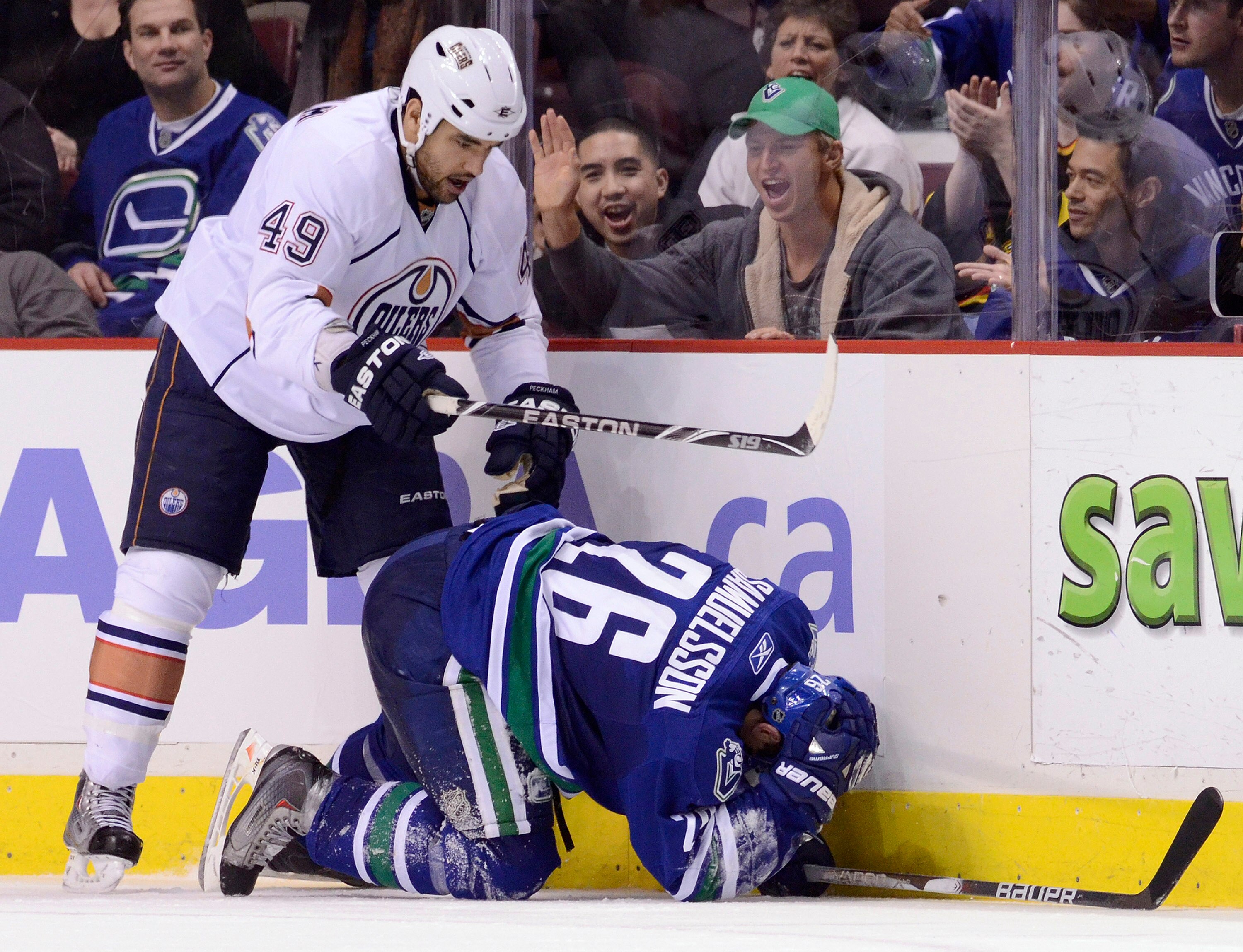 VANCOUVER, CANADA - JANUARY 7: Theo Peckham #49 of the Edmonton Oilers hits Mikael Samuelsson #26 of the Vancouver Canucks while down on the ice during the third period at Rogers Arena January 7, 2011 in Vancouver, BC, Canada. Peckham was assessed a minor