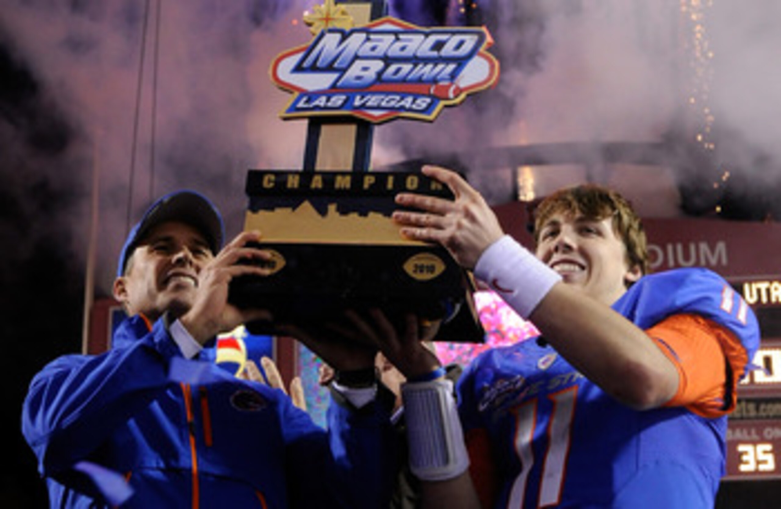 LAS VEGAS, NV - DECEMBER 22:  Head coach Chris Petersen (L) and quarterback Kellen Moore #11 of the Boise State Broncos hold up a trophy as they celebrate their 26-3 victory over the Utah Utes in the MAACO Bowl Las Vegas at Sam Boyd Stadium December 22, 2