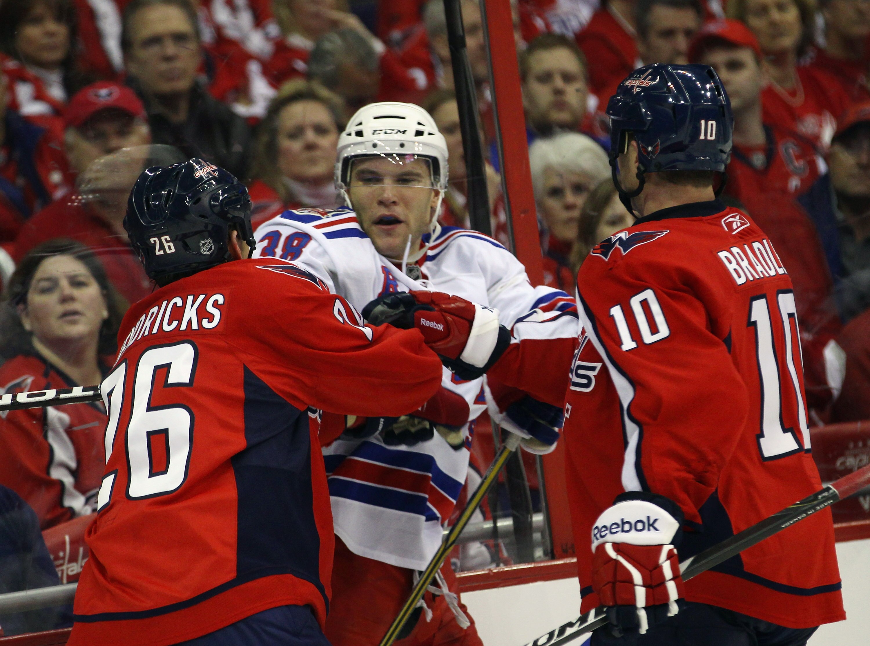 WASHINGTON, DC - APRIL 13: Michael Sauer #38 of the New York Rangers is taken on by Matt Hendricks #26 and Matt Bradley #10 of the Washington Capitals in Game One of the Eastern Conference Quarterfinals during the 2011 NHL Stanley Cup Playoffs at Verizon