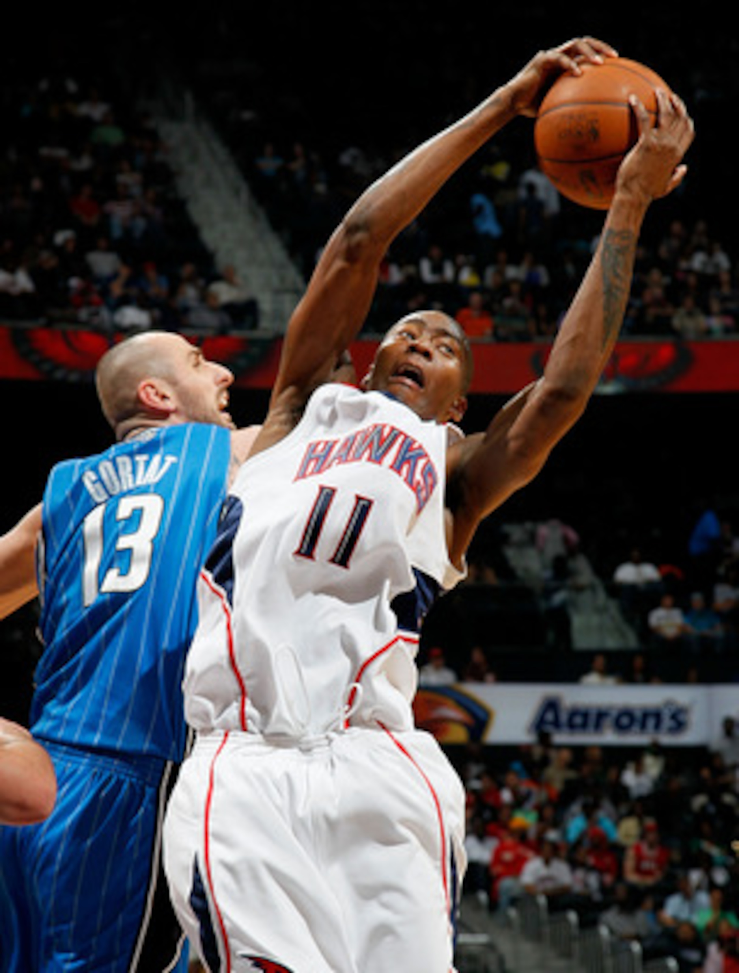 ATLANTA - MARCH 24:  Jamaal Crawford #11 of the Atlanta Hawks grabs a rebound against Marcin Gortat #13 of the Orlando Magic at Philips Arena on March 24, 2010 in Atlanta, Georgia.  NOTE TO USER: User expressly acknowledges and agrees that, by downloading