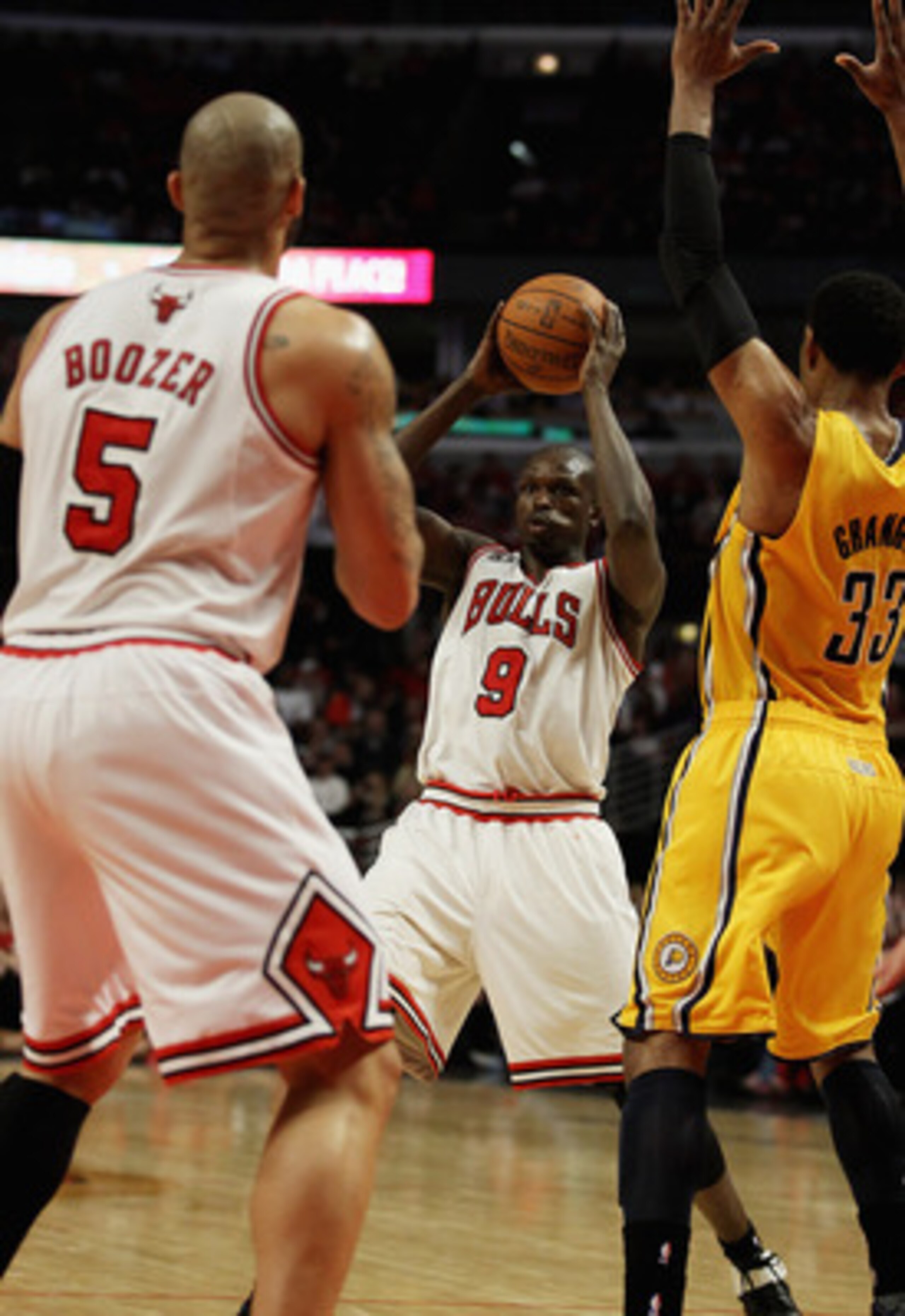 CHICAGO, IL - APRIL 26: Loul Deng #9 of the Chicago Bulls looks to pass to teammate Carlos Boozer #5 under pressure from Danny Granger #33 of the Indiana Pacers in Game Five of the Eastern Conference Quarterfinals in the 2011 NBA Playoffs at the United Ce