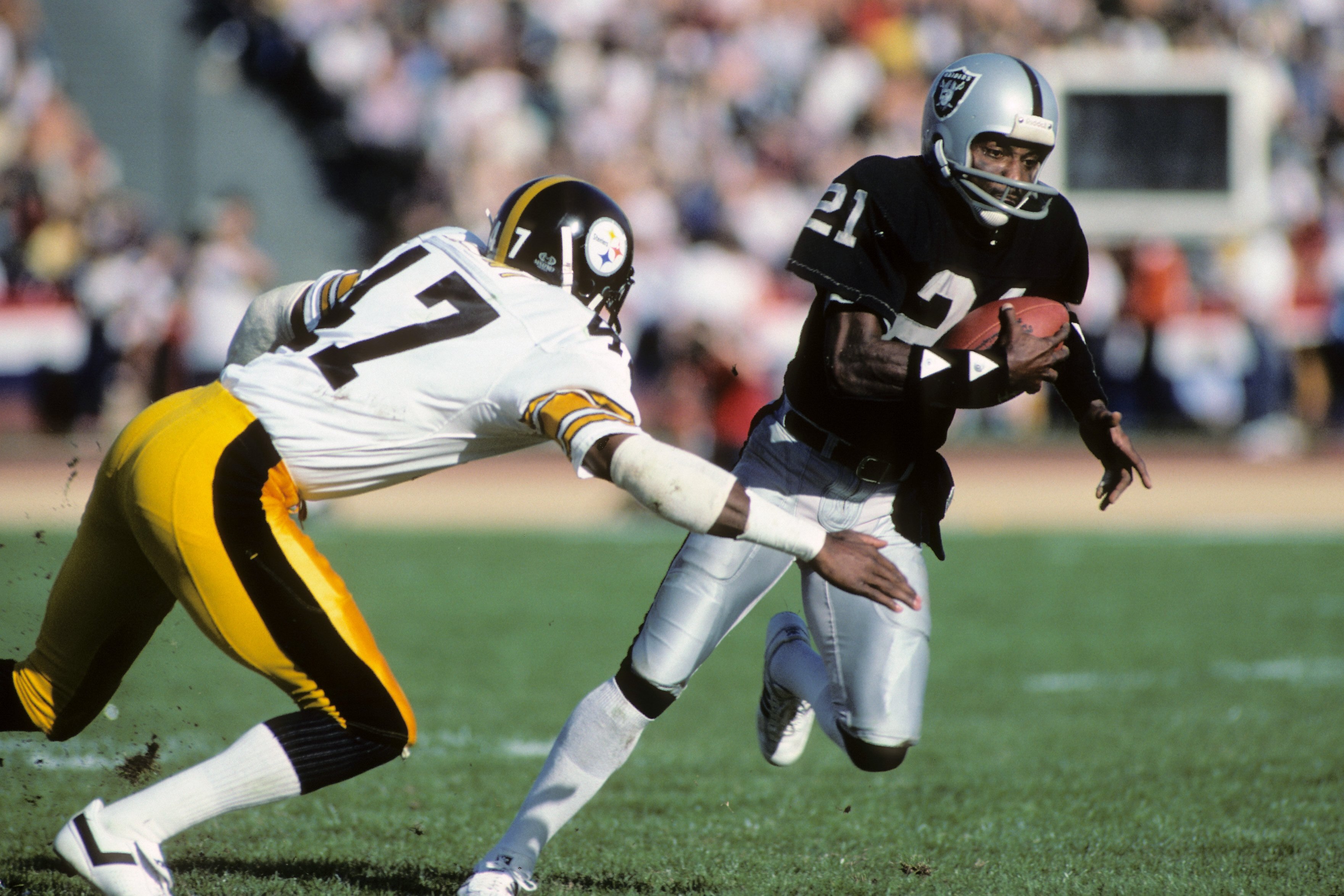 LOS ANGELES, CA - JANUARY 1:  Cliff Branch #21 of the Los Angeles Raiders runs the ball against Mel Blount #47 of the Pittsburgh Steelers during the AFC Divisional playoff game at the Los Angeles Memorial Coliseum on January 1, 1984 in Los Angeles, Califo