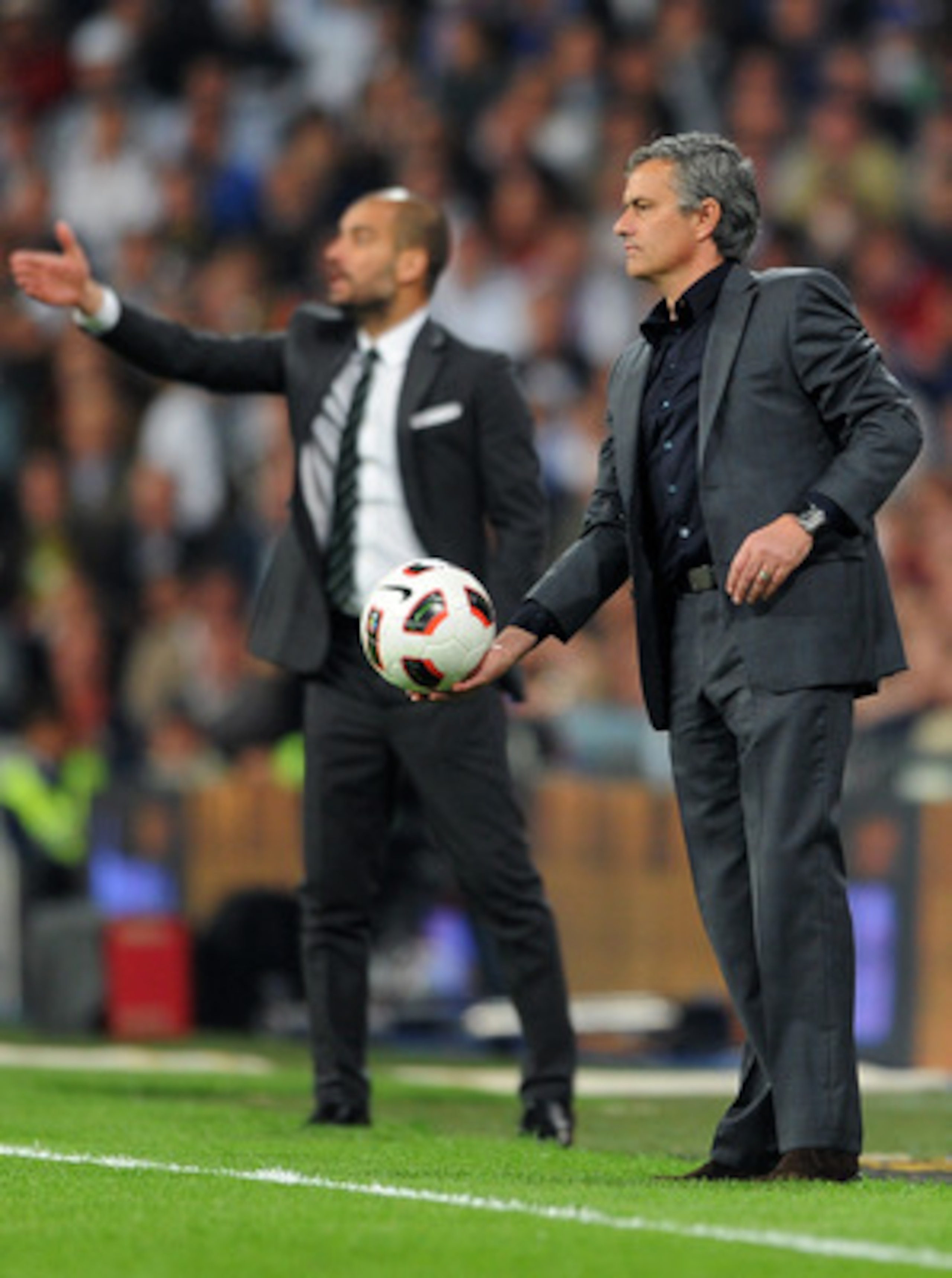 MADRID, SPAIN - APRIL 16:  Head coach Jose Mourinho (R) of Real Madrid throws the ball backdropped by head coach Josep Guardiola of Barcelona during the la Liga match between Real Madrid and Barcelona at Estadio Santiago Bernabeu on April 16, 2011 in Madr