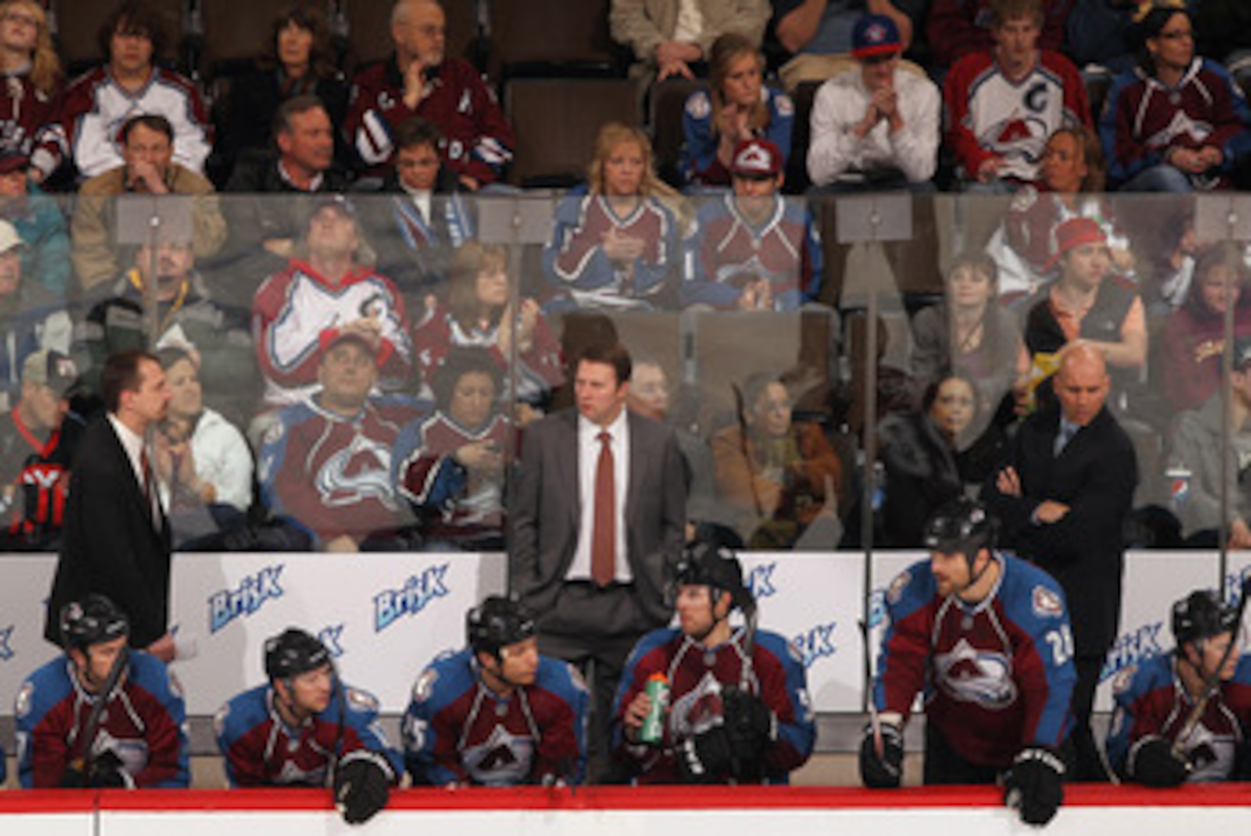 DENVER, CO - FEBRUARY 14: (L-R) Assistant coach Steve Konowalchuk, head coach Joe Sacco and assistant coach Sylvain Lefebvre of the Colorado Avalanche stand behind the players on the bench and in front of the on looking fans as the Avalanche were defeate DENVER, CO - FEBRUARY 14: (L-R) Assistant coach Steve Konowalchuk, head coach Joe Sacco and assistant coach Sylvain Lefebvre of the Colorado Avalanche stand behind the players on the bench and in front of the on looking fans as the Avalanche were defeate