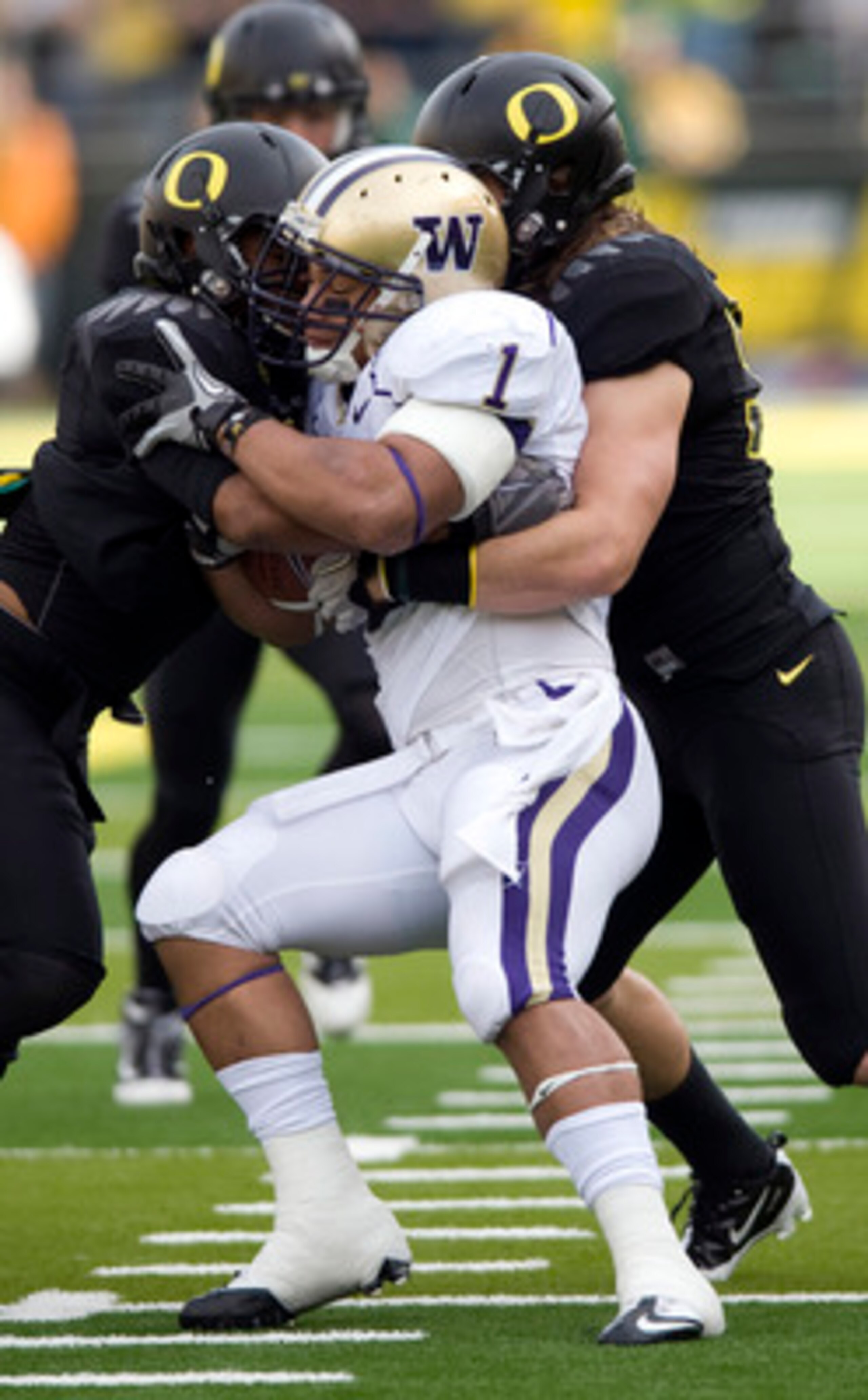 EUGENE, OR - NOVEMBER 6: Linebackers Spencer Paysinger #35 and Casey Matthews #55 of the Oregon Ducks gang up to tackle running back Chris Polk #1 of the Washington Huskies in the first quarter of the game at Autzen Stadium on November 6, 2010 in Eugene, 