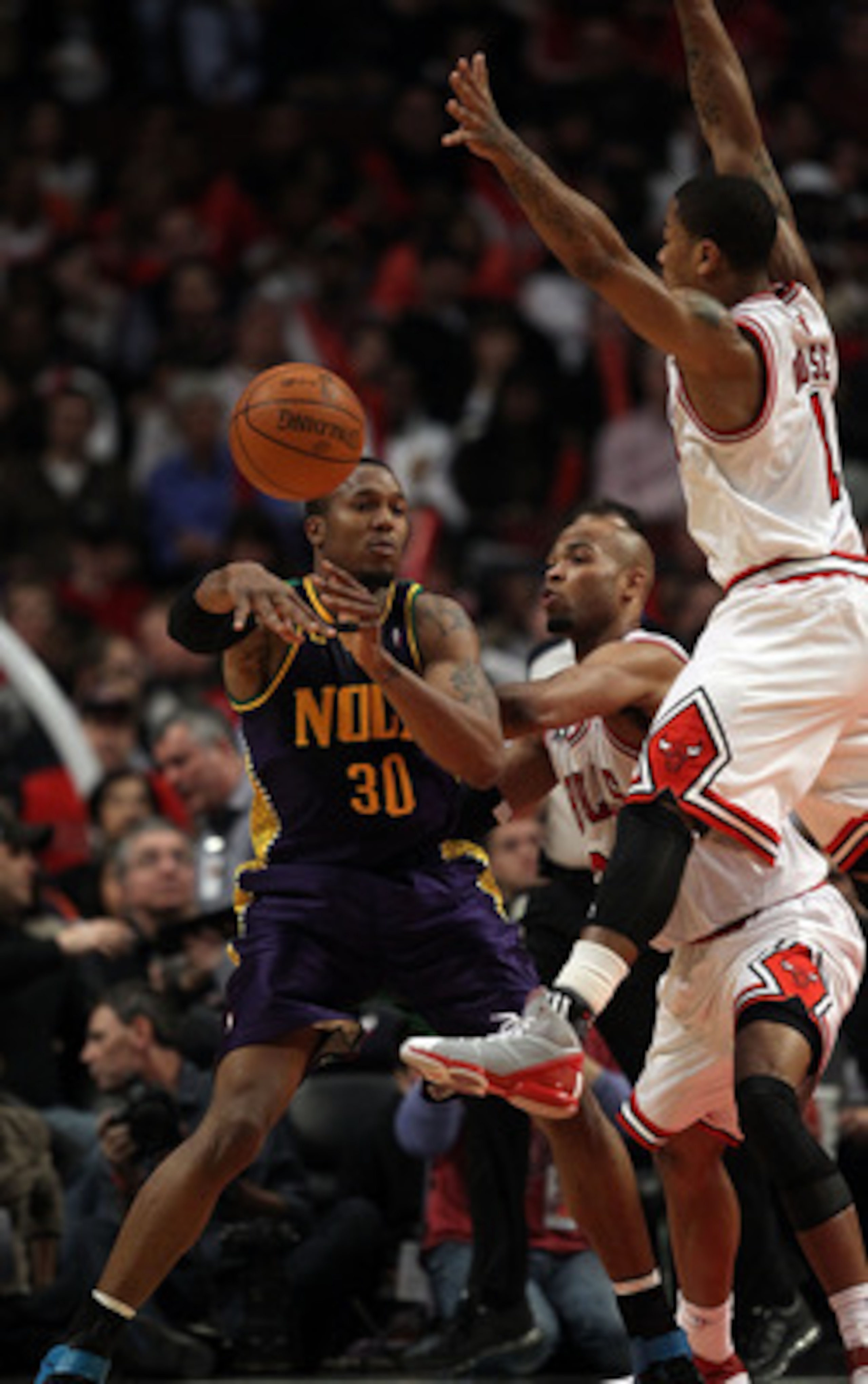 CHICAGO, IL - MARCH 07: David West #30 of the New Orleans Hornets passes the ball as Derrick Rose #1 of the Chicago Bulls leaps to try for the block at the United Center on March 7, 2011 in Chicago, Illinois. The Bulls defeated the Hornets 85-77. NOTE TO 