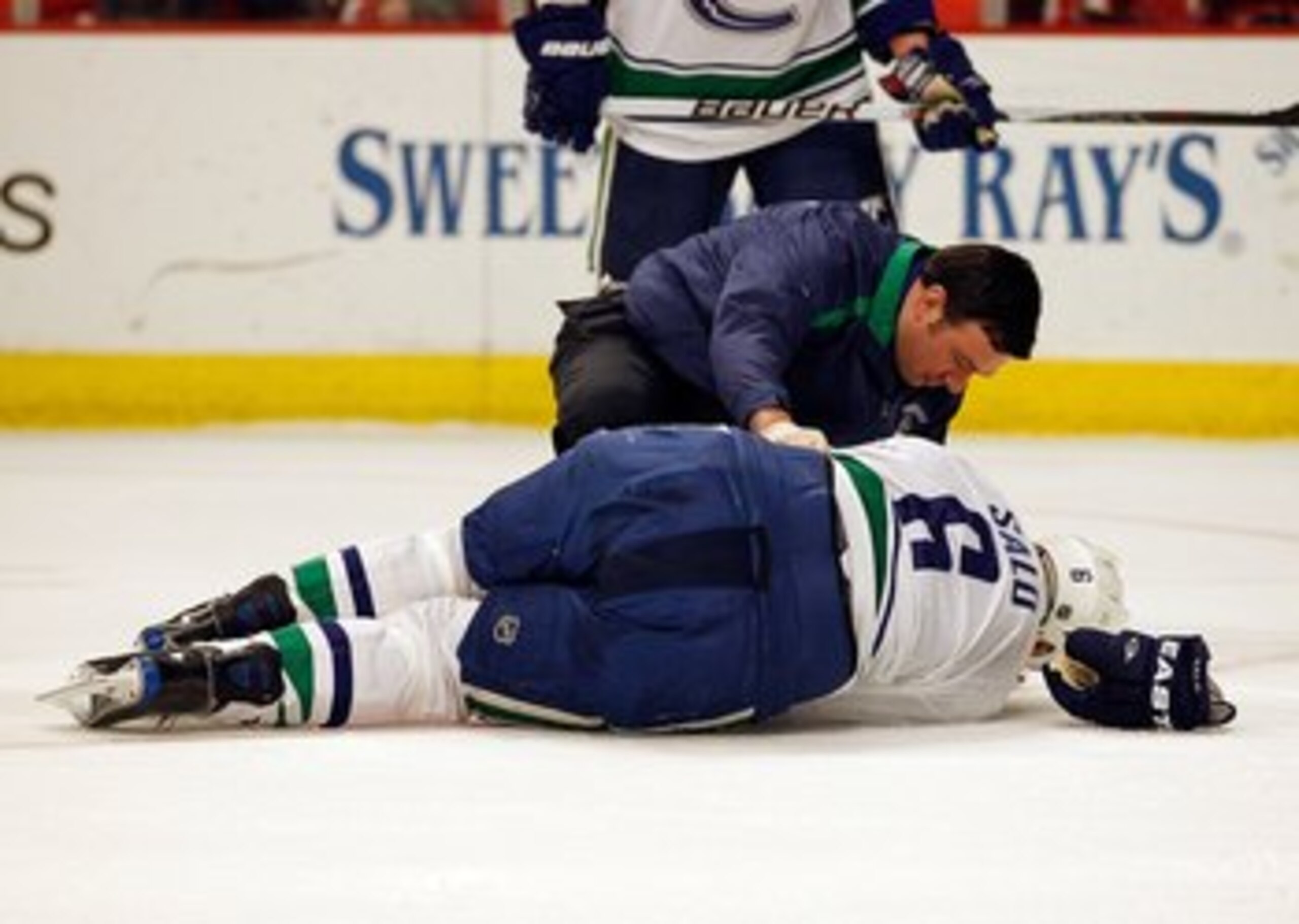 CHICAGO - MAY 09: A trainer attends to Sami Salo #6 of the Vancouver Canucks at the end of the first period after Salo suffered an injury against the Chicago Blackhawks in Game Five of the Western Conference Semifinals during the 2010 NHL Stanley Cup Play