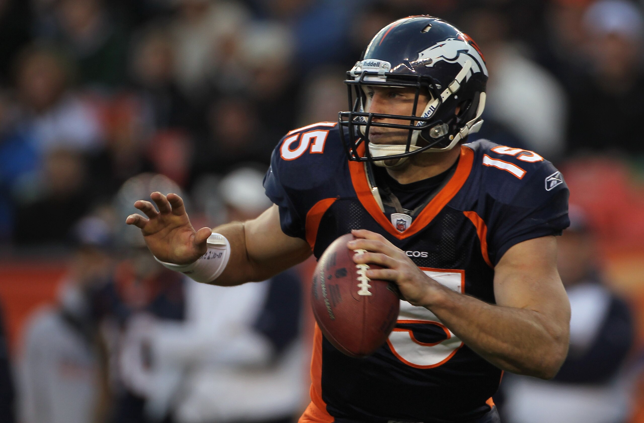 DENVER - DECEMBER 26:  Quarterback Tim Tebow #15 of the Denver Broncos rolls out and looks to deliver a pass against the Houston Texas at INVESCO Field at Mile High on December 26, 2010 in Denver, Colorado. The Broncos defeated the Texans 24-23.  (Photo b