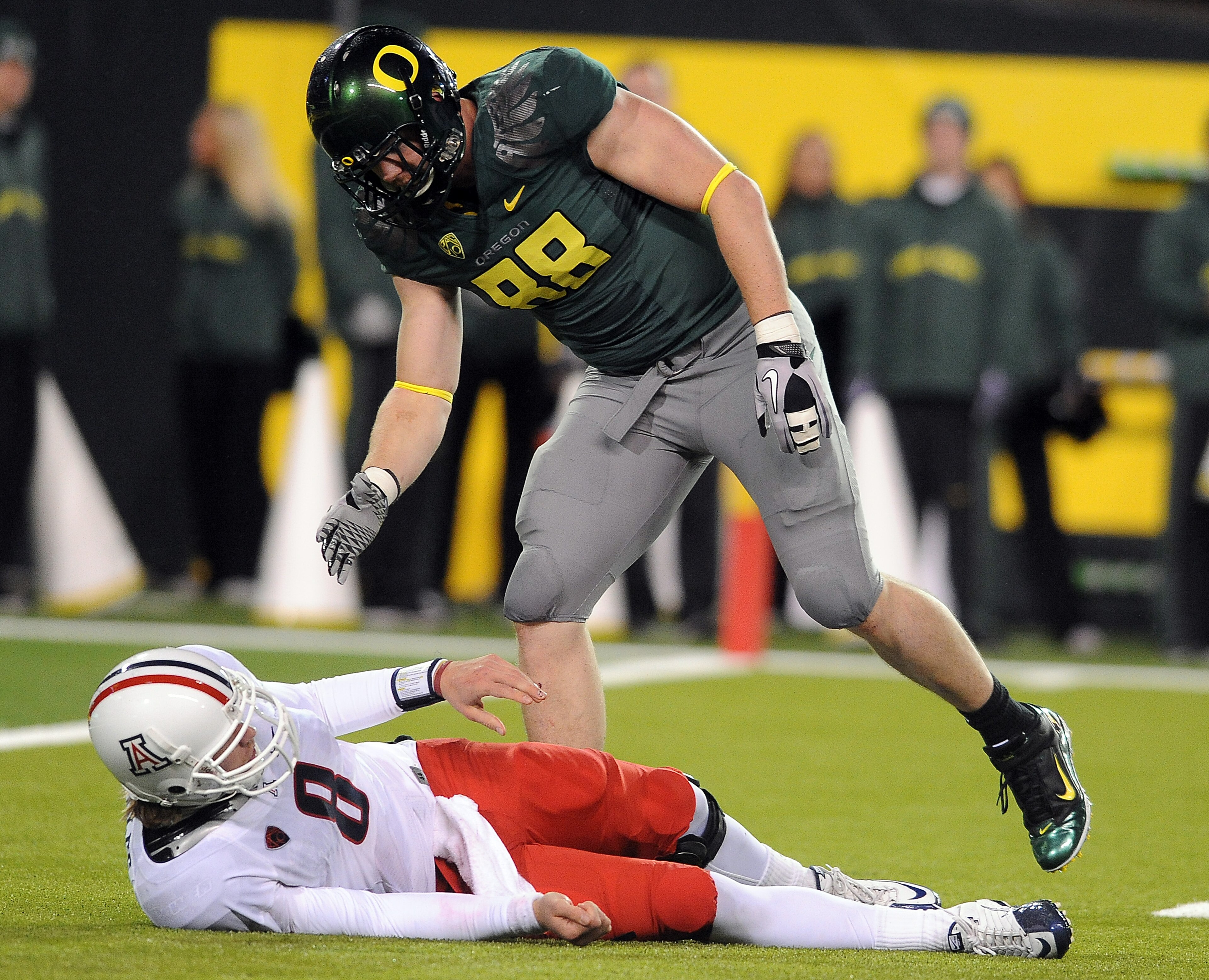 EUGENE, OR - NOVEMBER 26: Quarterback Nick Foles #8 of the Arizona Wildcats is helped up by defensive end Brandon Bair #88 of the Oregon Ducks in the fourth quarter of the game at Autzen Stadium on November 26, 2010 in Eugene, Oregon. The Ducks won the ga EUGENE, OR - NOVEMBER 26: Quarterback Nick Foles #8 of the Arizona Wildcats is helped up by defensive end Brandon Bair #88 of the Oregon Ducks in the fourth quarter of the game at Autzen Stadium on November 26, 2010 in Eugene, Oregon. The Ducks won the ga