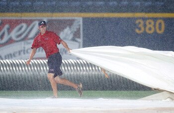 ATLANTA - MAY 28:  A member of the grounds crew pulls the tarp over the infield after a delay in play was called due to rain during the game between the Atlanta Braves and the Pittsburgh Pirates at Turner Field on May 28, 2010 in Atlanta, Georgia.  (Photo