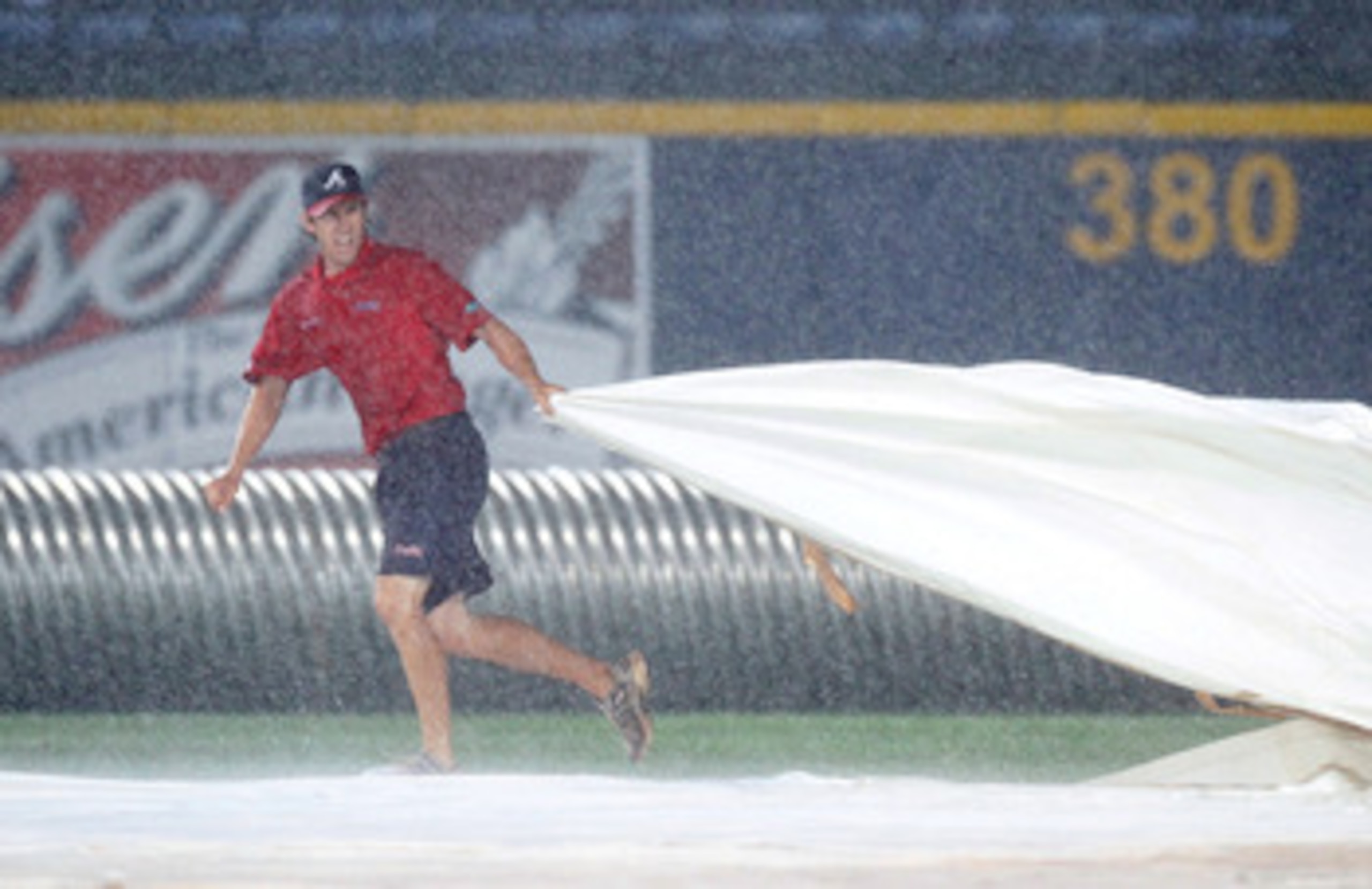 ATLANTA - MAY 28:  A member of the grounds crew pulls the tarp over the infield after a delay in play was called due to rain during the game between the Atlanta Braves and the Pittsburgh Pirates at Turner Field on May 28, 2010 in Atlanta, Georgia.  (Photo