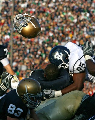 SOUTH BEND, IN - NOVEMBER 21: Armando Allen #5 of the Notre Dame Fighting Irish looses his helmut as he is hit at the goalline by Greg Lloyd #95 of the Univeristy of Connecticut Huskies at Notre Dame Stadium on November 21, 2009 in South Bend, Indiana. (P