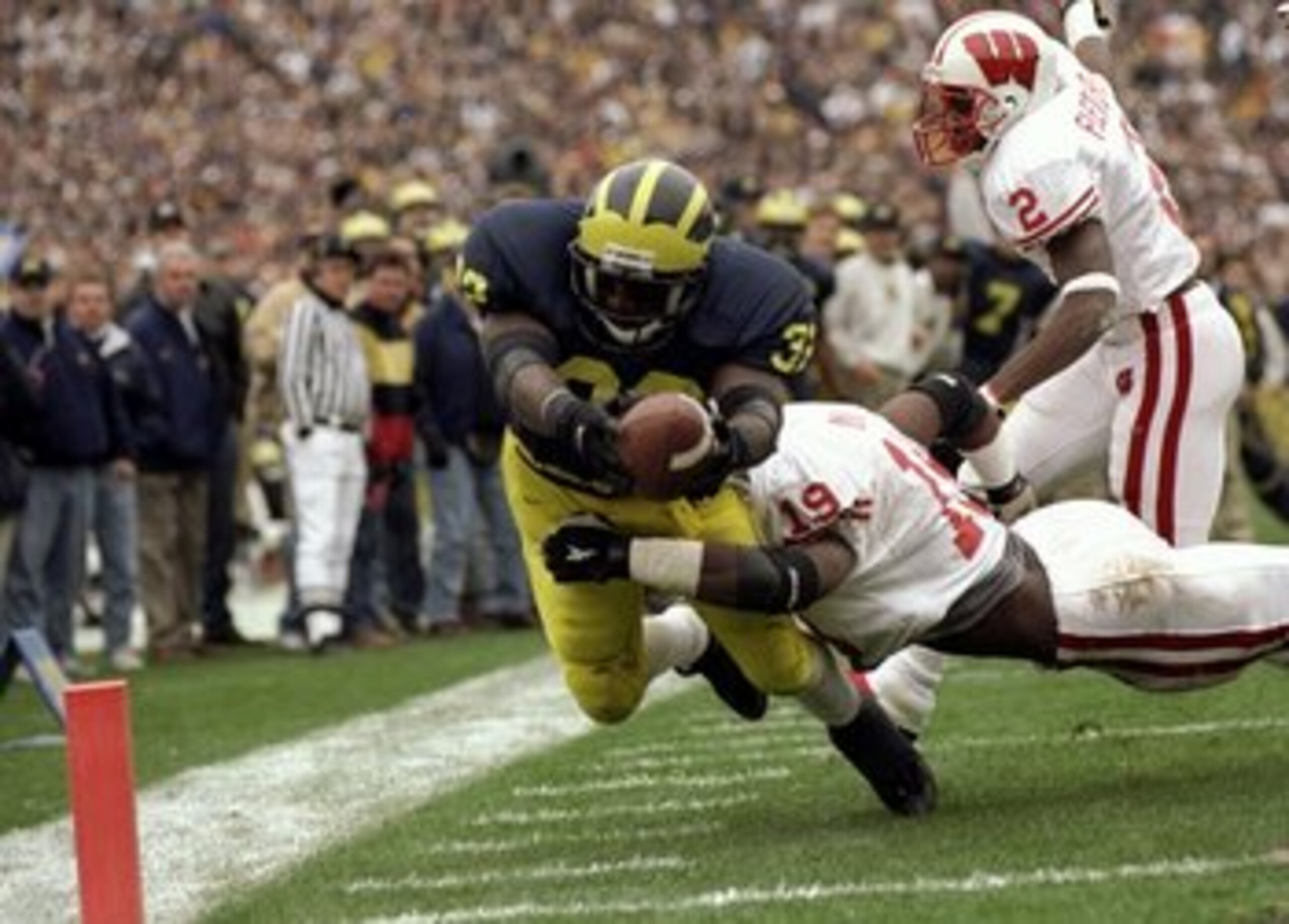 14 Nov 1998:  Tailback Anthony Thomas #32 of the Michigan Wolverines dives across the goal line with the ball while being tackled by Roger Knight #19 of the Wisconsin Badgers during a game at the Michigan Stadium in Ann Arbor, Michigan. The Wolverines def