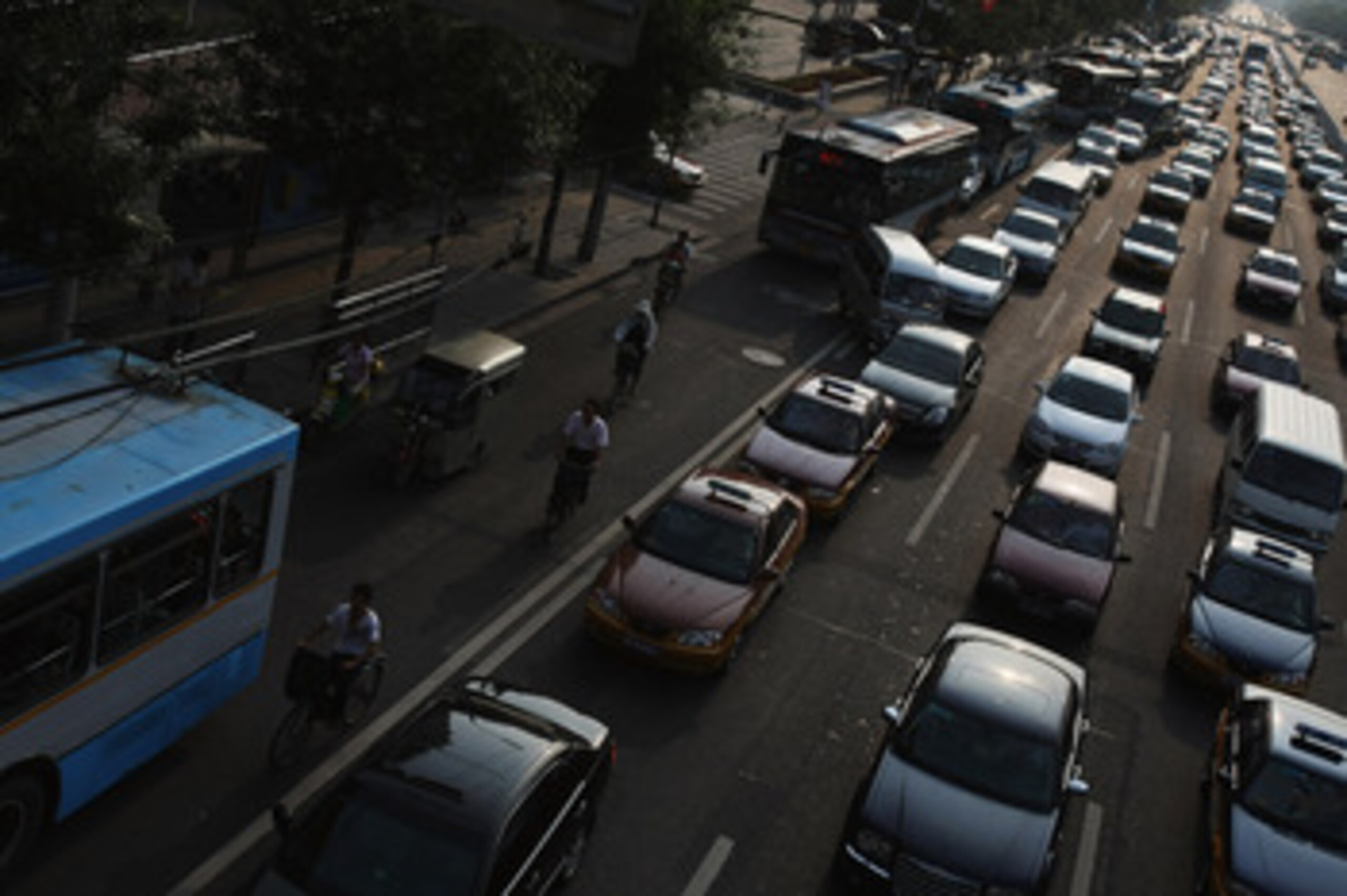 BEIJING - AUGUST 12:  Chinese cyclists manoeuvre through a heavy traffic jam in the city center on August 12, 2008 in Beijing, China. The Chinese capital enforced a traffic ban based on the parity of licence plate numbers to keep vehicles off the roads on