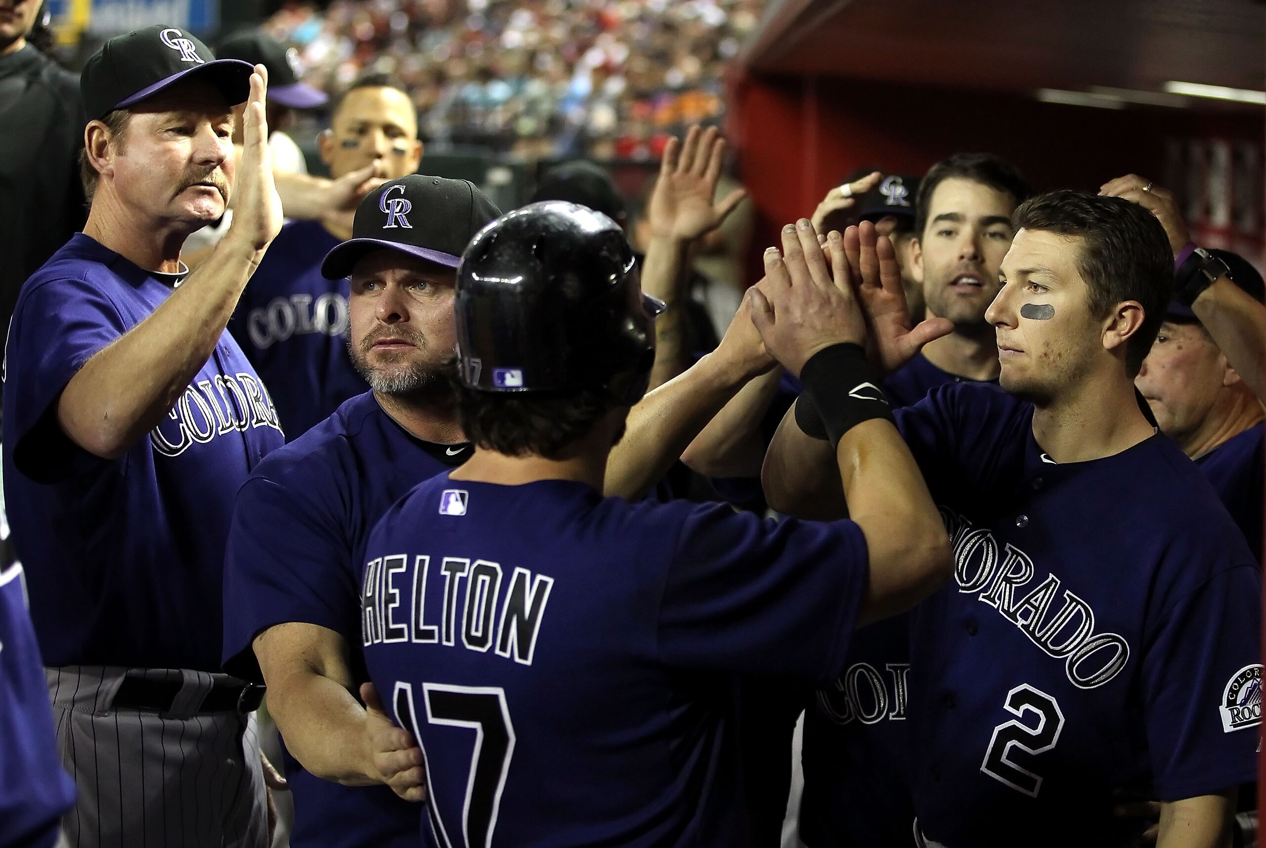 PHOENIX, AZ - MAY 05:  Todd Helton #17 of the Colorado Rockies high fives teammates Carney Lansford, Jason Giambi #23 and Troy Tulowitzki #2 after Helton scored a fourth inning run against the Arizona Diamondbacks during the Major League Baseball game at