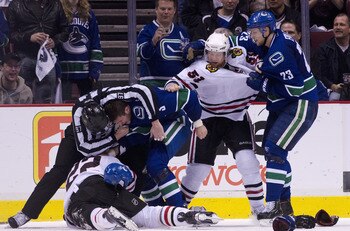 VANCOUVER, CANADA - APRIL 21: Linesman Jean Morin #97 tries to separate Kevin Bieksa #3 of the Vancouver Canucks and Troy Brouwer #22 of the Chicago Blackhawks while Alexander Edler #23 of the Vancouver Canucks  and Brian Campbell #51 of the Chicago Black