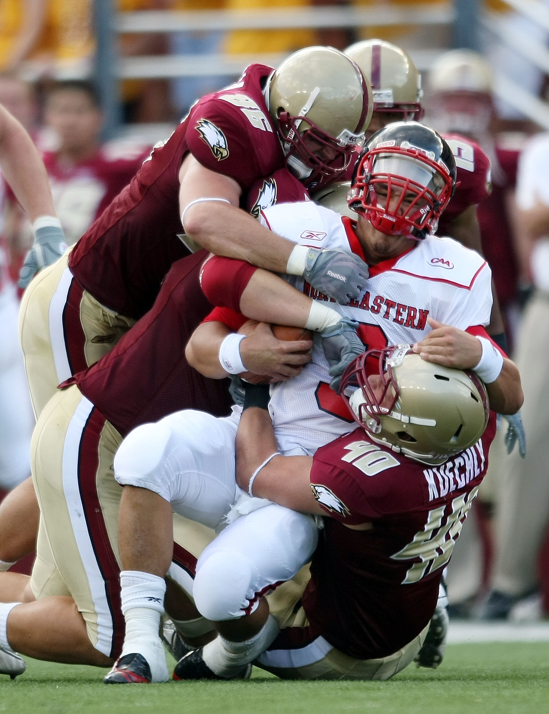 CHESTNUT HILL, MA - SEPTEMBER 05:  Matt Carroll #3 of the Northeastern Huskies is tackled by Dillon Quinn #92,Kaleb Ramsey #96 and Luke Kuechly #40  of the Boston College Eagles on September 5, 2009 at Alumni Stadium in Chestnut Hill, Massachusetts.  (Pho