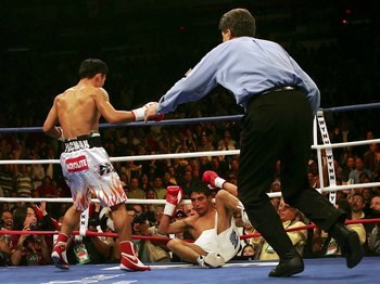 LAS VEGAS - NOVEMBER 18:  (L-R) Manny Pacquiao of the Philippines looks down as Erik Morales of Mexico is knocked down for the second time in round three during their super featherweight bout at the Thomas & Mack Center on November 18, 2006 in Las Vegas,
