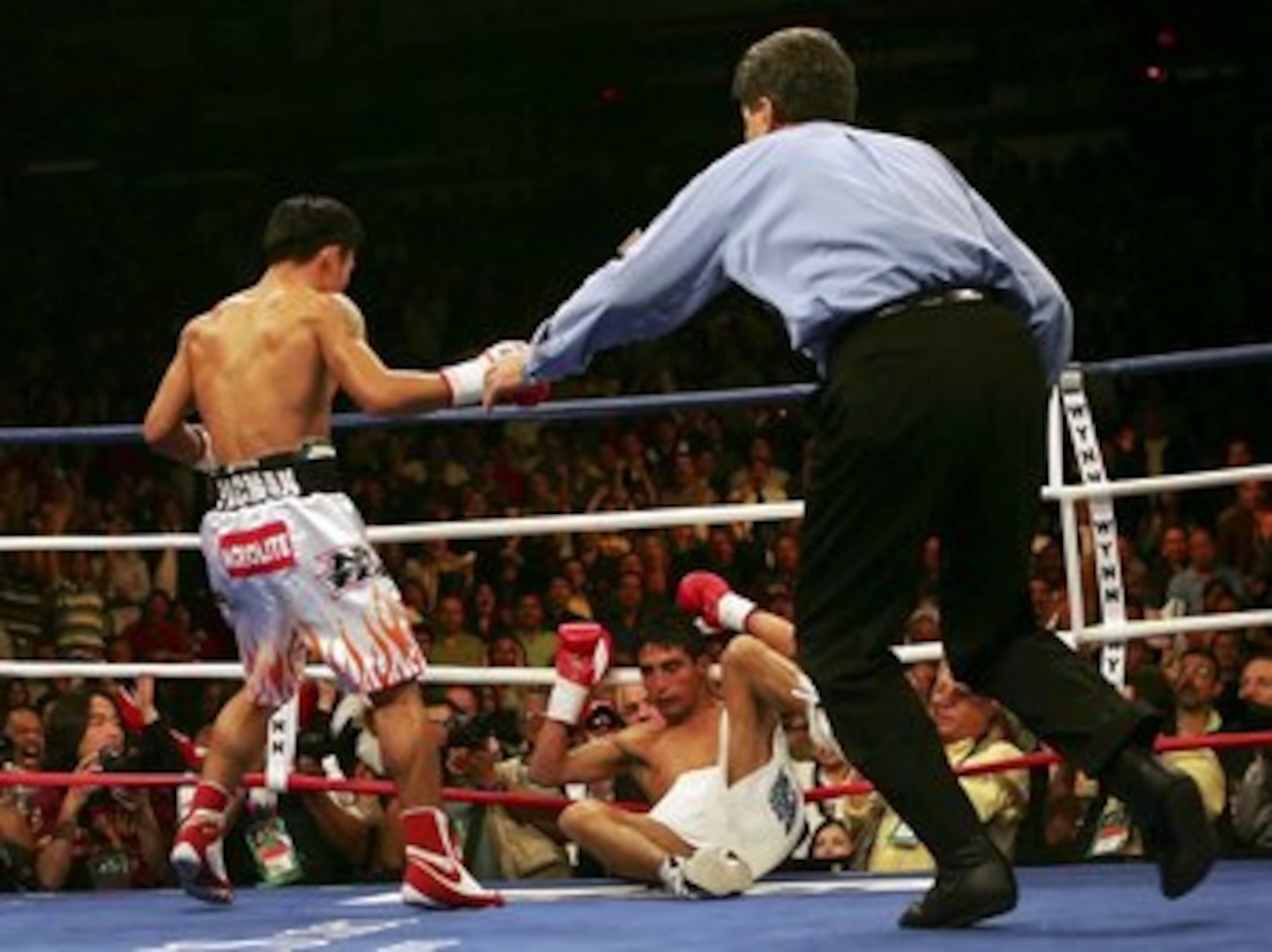 LAS VEGAS - NOVEMBER 18:  (L-R) Manny Pacquiao of the Philippines looks down as Erik Morales of Mexico is knocked down for the second time in round three during their super featherweight bout at the Thomas & Mack Center on November 18, 2006 in Las Vegas,