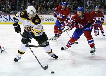 MONTREAL, CANADA - APRIL 26:  Brad Marchand #63 of the Boston Bruins controls the puck along the near boards while being pursued by Travis Moen #32 of the Montreal Canadiens in Game Six of the Eastern Conference Quarterfinals during the 2011 NHL Stanley C