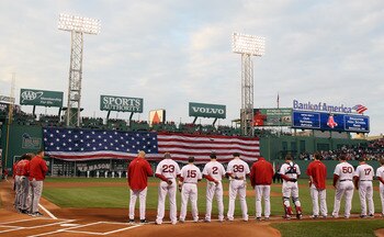 BOSTON, MA - MAY 02:  The Boston Red Sox and the Los Angeles Angels watch the flag cover the Green Monster as the national anthem is played on May 2, 2011 at Fenway Park in Boston, Massachusetts.  Both teams lined up on the baseline to observe a moment of