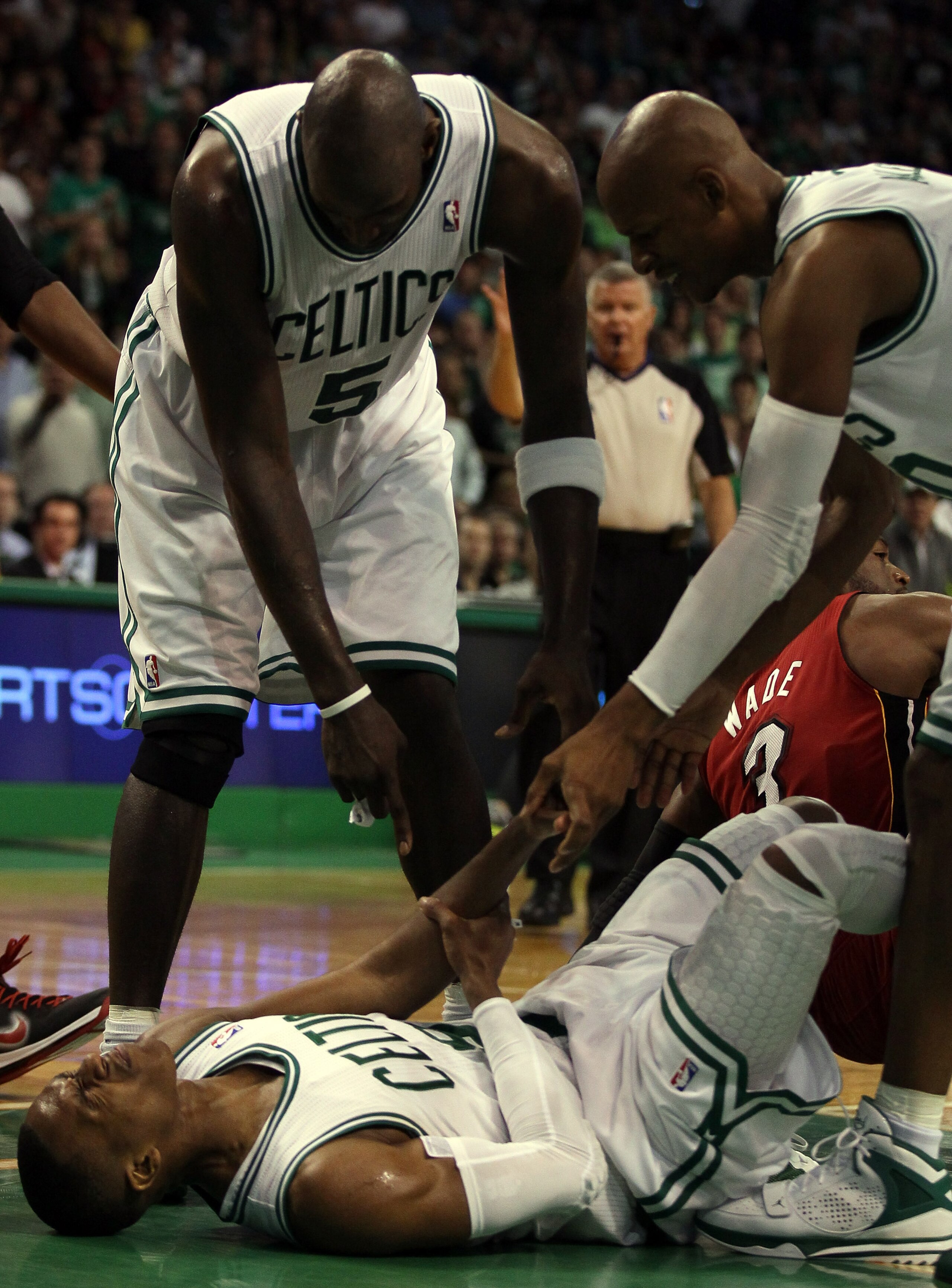 BOSTON, MA - MAY 07:  Kevin Garnett #3 and Ray Allen #20 try to help up teammate Rajon Rondo #9 of the Boston Celtics after he is knocked down by Dwyane Wade #3 of the Miami Heat in Game Three of the Eastern Conference Semifinals in the 2011 NBA Playoffs 