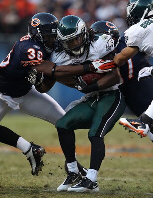 CHICAGO - NOVEMBER 28: Jorrick Calvin #38 of the Philadelphia Eagles is tackled by D.J. Moore #30 and Kellen Davis #87 of the Chicago Bears at Soldier Field on November 28, 2010 in Chicago, Illinois. The Bears defeated the Eagles 31-26. (Photo by Jonathan