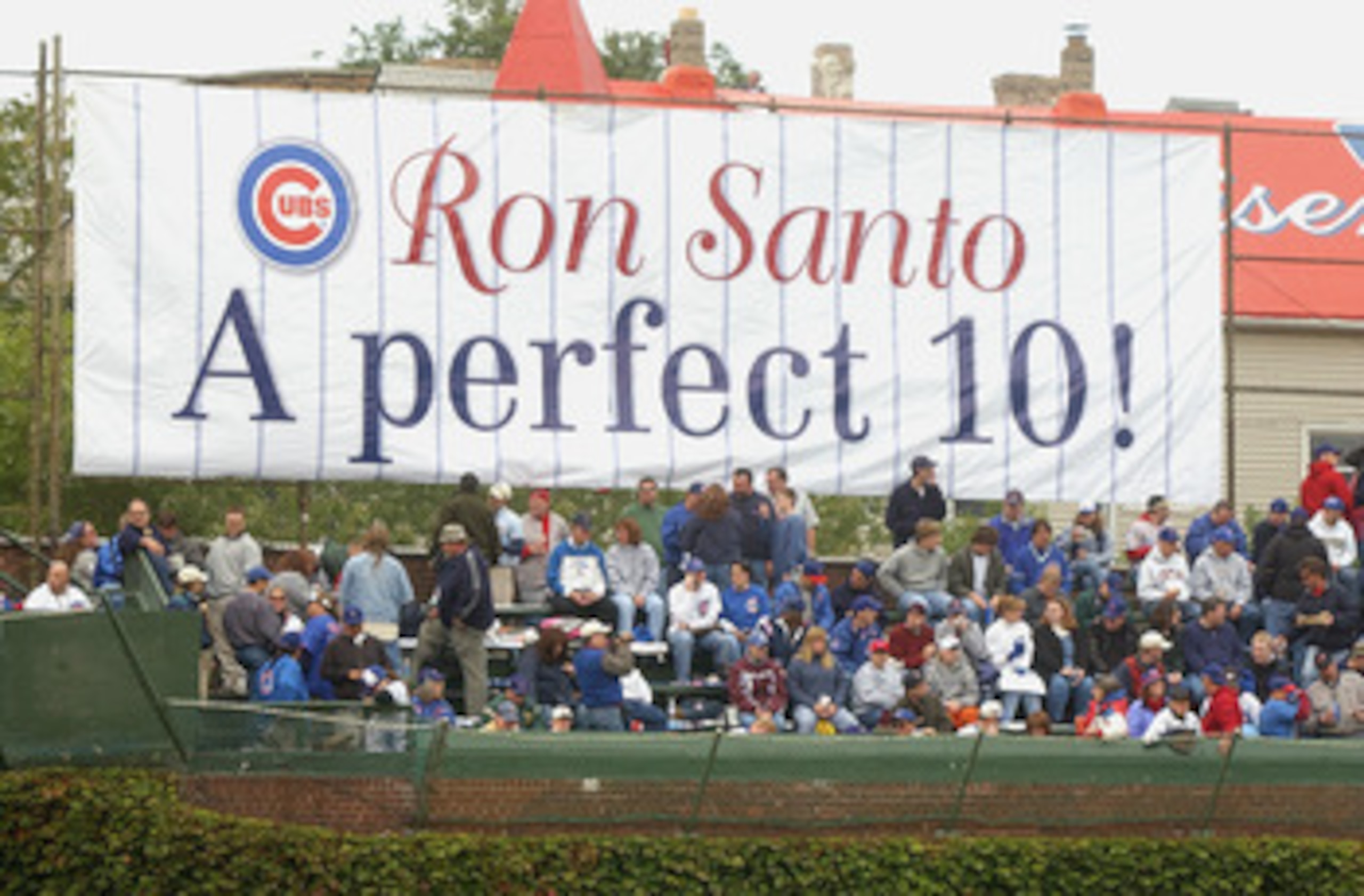 CHICAGO - SEPTEMBER 28: Fans of the Chicago Cubs watch the game in front of a sign honoring longtime Cubs third baseman and current WGN Radio color commentator Ron Santo (Santo's number 10 was retired in a pregame ceremony) during a game against the Pitt CHICAGO - SEPTEMBER 28: Fans of the Chicago Cubs watch the game in front of a sign honoring longtime Cubs third baseman and current WGN Radio color commentator Ron Santo (Santo's number 10 was retired in a pregame ceremony) during a game against the Pitt