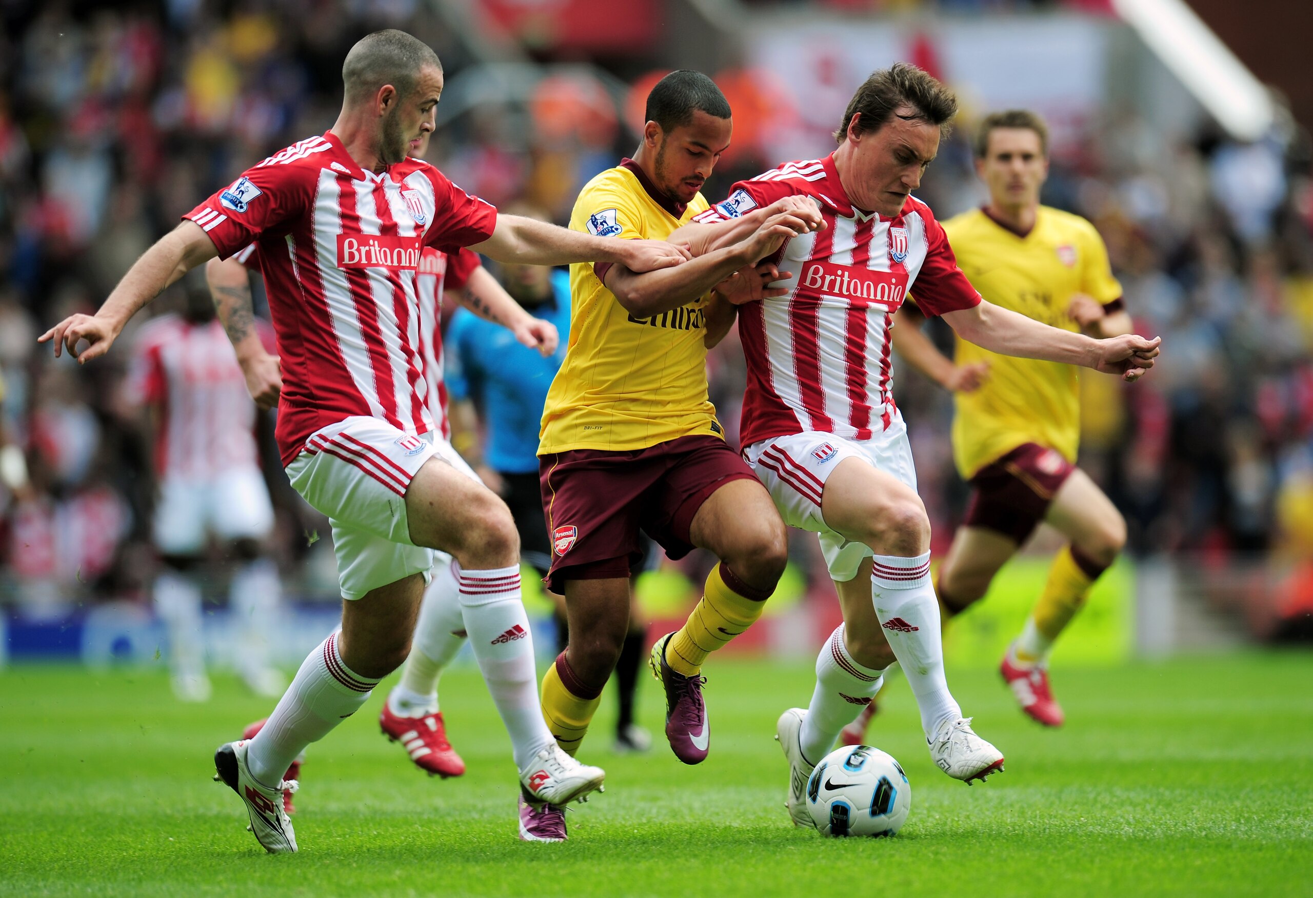 STOKE ON TRENT, ENGLAND - MAY 08:  Theo Walcott of Arsenal is closed down by Marc Wilson (L) and Dean Whitehead (R) of Stoke during the Barclays Premier League match between Stoke City and Arsenal at the Britannia Stadium on May 8, 2011 in Stoke on Trent,
