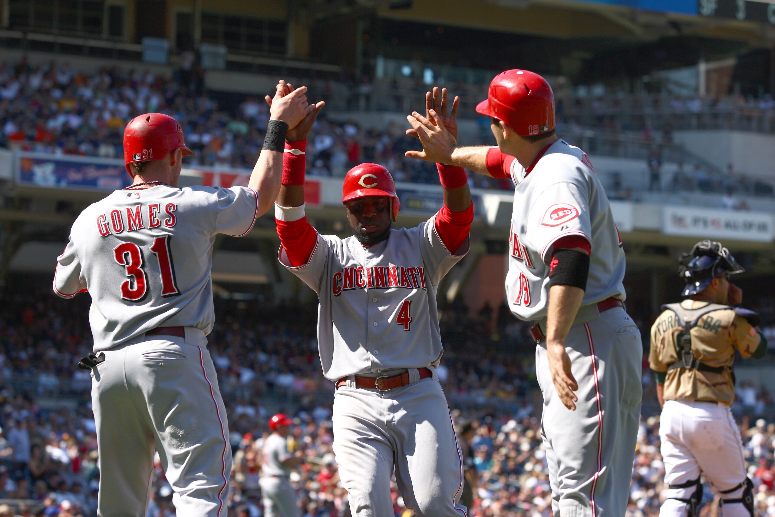 SAN DIEGO, CA - SEPTEMBER 26:  Jonny Gomez #31 and Joey Votto #19 congratulate Brandon Phillips #4 of Cincinnati Reds after their teammate Chris Heisey #28 hit a 3-RBI double against the San Diego Padres during the 4th inning of their MLB game on Septembe