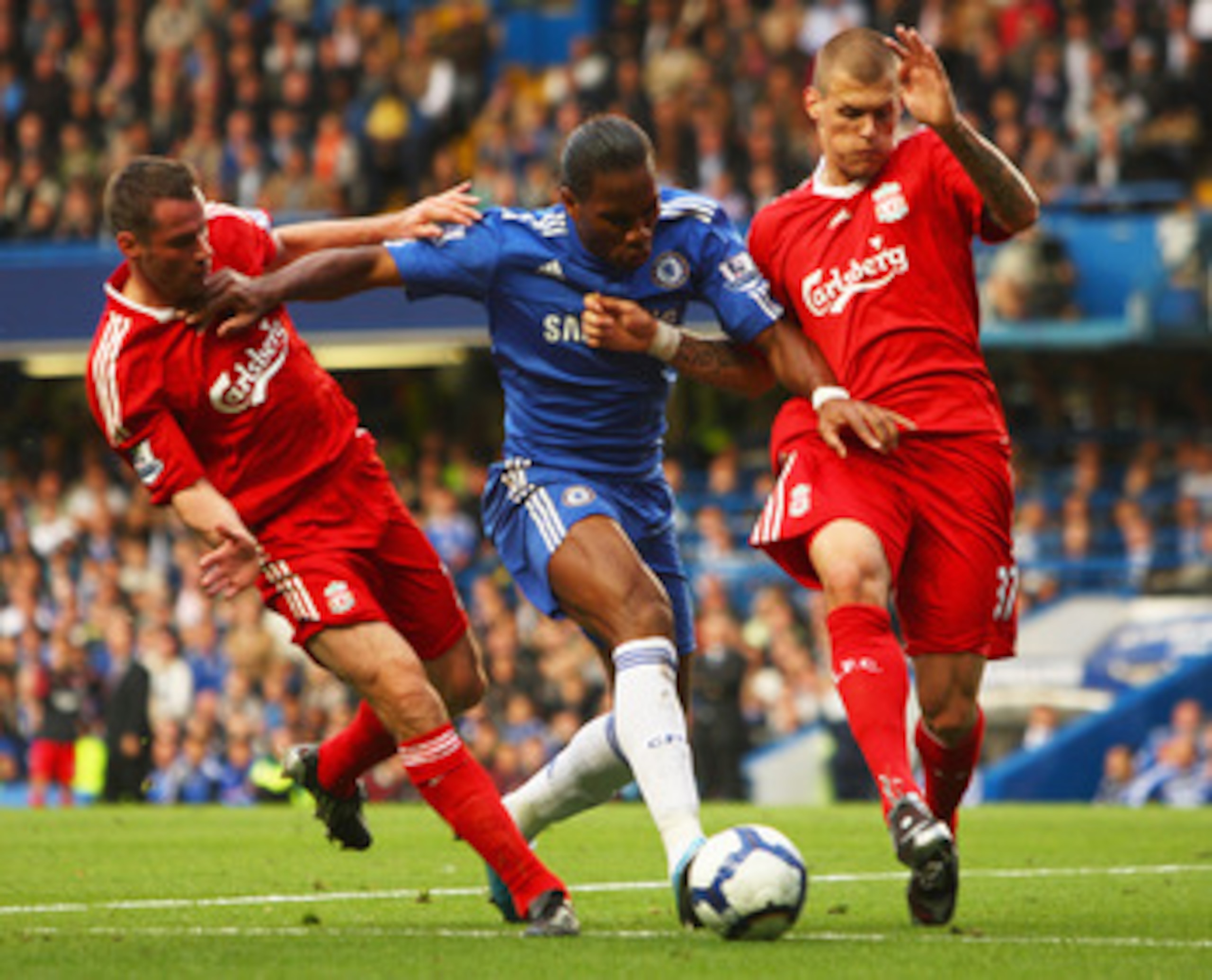 LONDON - OCTOBER 04:  Martin Skrtel (R) and Jamie Carragher of Liverpool (L) tussle with Didier Drogba of Chelsea during the Barclays Premier League match between Chelsea and Liverpool at Stamford Bridge on October 4, 2009 in London, England.  (Photo by I