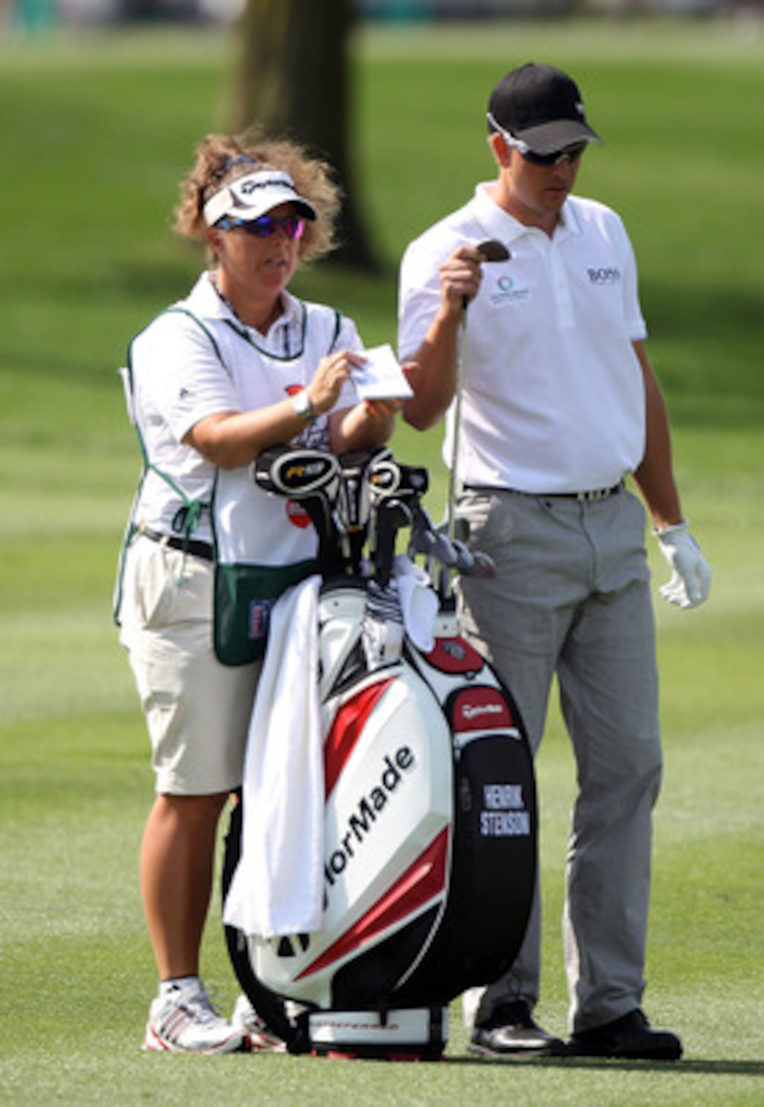 ORLANDO, FL - MARCH 25:  Henrik Stenson of Sweden pulls a club in the first fairway as his caddie Fanny Sunnesson looks on during the first round of the Arnold Palmer Invitational presented by MasterCard at the Bayhill Club and Lodge on March 25, 2010 in