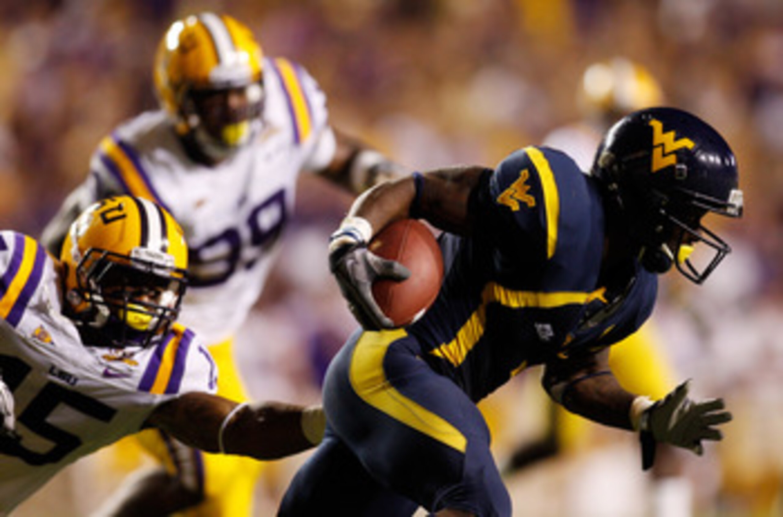 BATON ROUGE, LA - SEPTEMBER 25:  Noel Devine #7 of the West Virginia Mountaineers avoids a tackle by Brandon Taylor #15 of the Louisiana State Univeristy Tigers at Tiger Stadium on September 25, 2010 in Baton Rouge, Louisiana.  The Tigers defeated the Mou