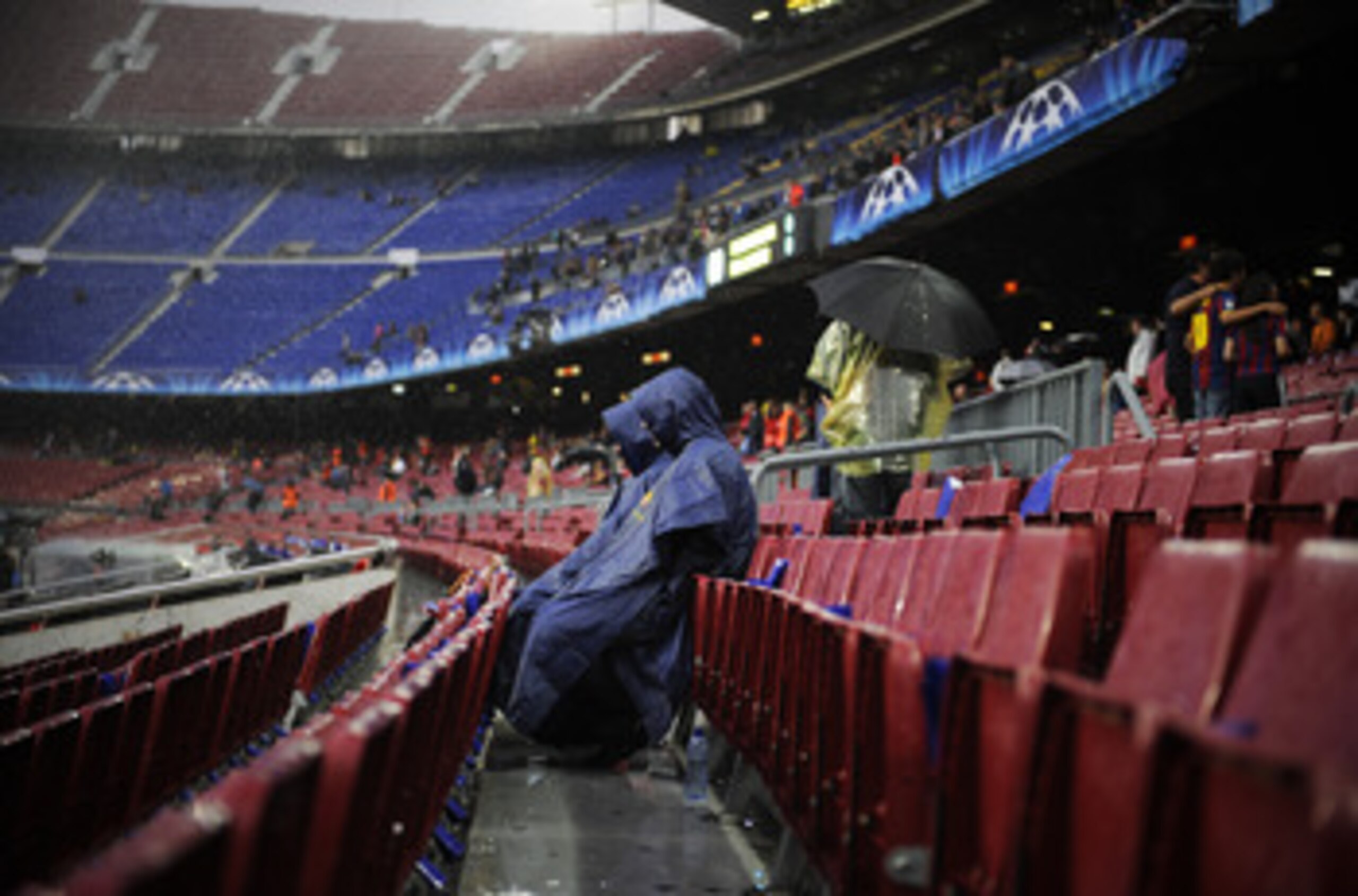 BARCELONA, SPAIN - MAY 03:  Two spectators sit on the  stands under heavy rain prior to the UEFA Champions League Semi Final second leg match between Barcelona and Real Madrid at the Nou Camp on May 3, 2011 in Barcelona, Spain.  (Photo by David Ramos/Gett