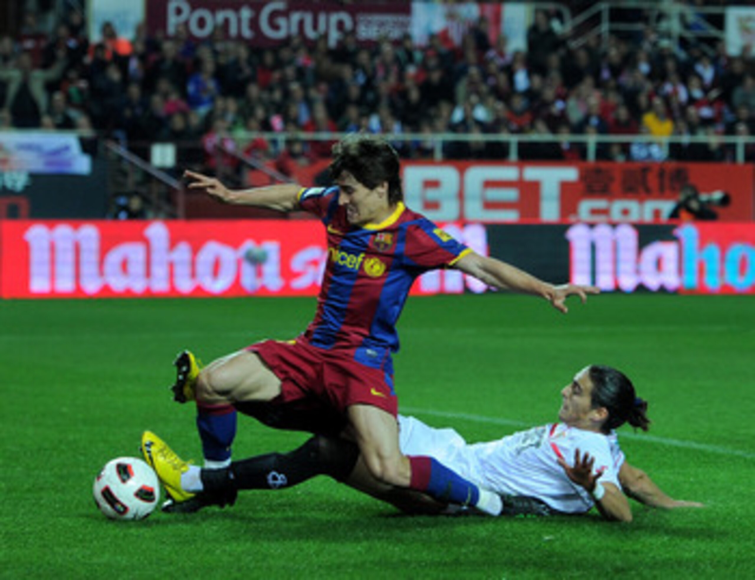 SEVILLE, SPAIN - MARCH 13:  Bojan Krkic (L) of Barcelona scores his sides opening goal past Jose Caceres of Sevilla during the la Liga match between Sevilla and Barcelona at Estadio Ramon Sanchez Pizjuan on March 13, 2011 in Seville, Spain.  (Photo by Jas