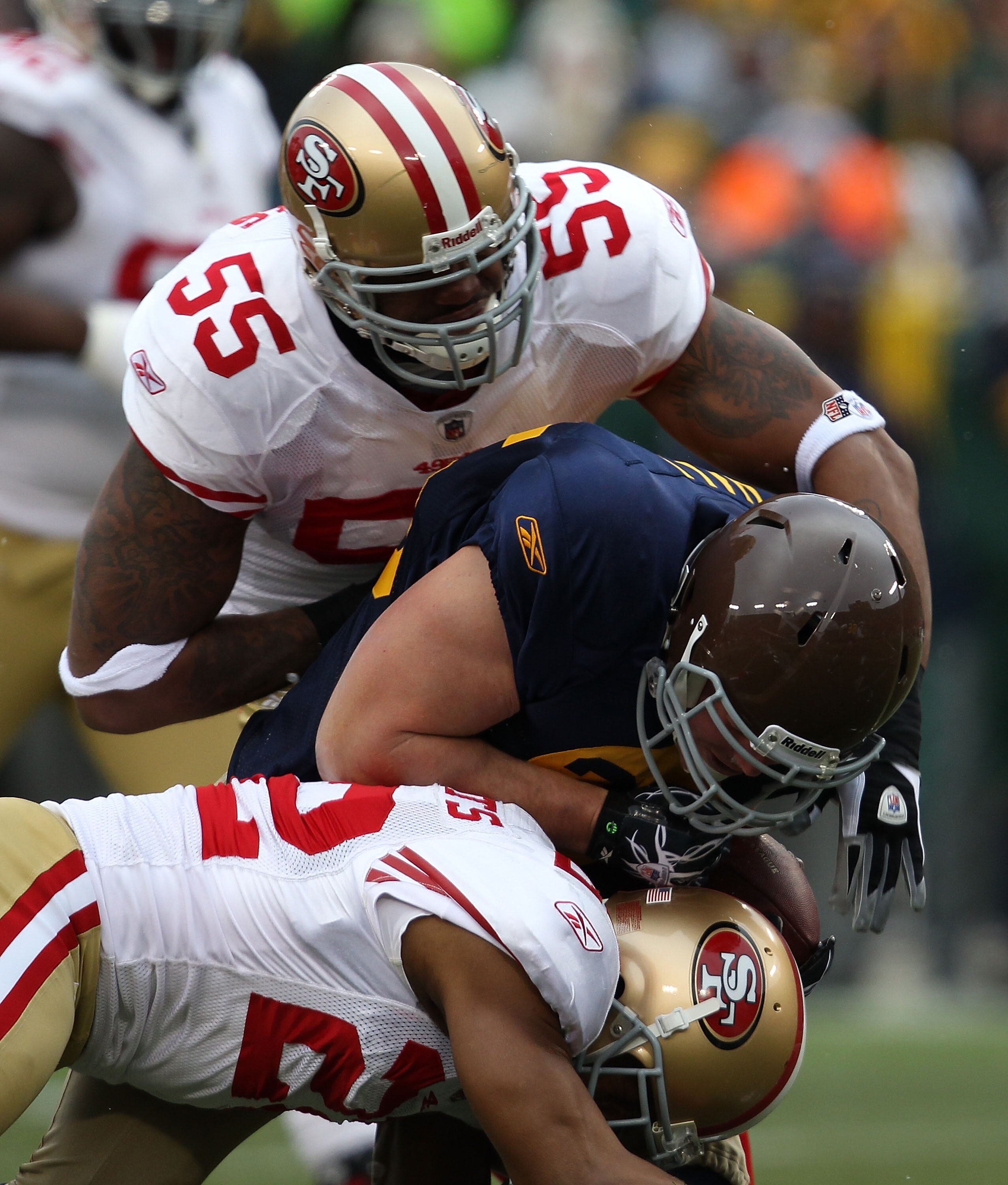 GREEN BAY, WI - DECEMBER 05: Ahmad Brooks #55 and Nate Clements #22 of the San Francisco 49ers tackle John Kuhn #30 of the Green Bay Packers at Lambeau Field on December 5, 2010 in Green Bay, Wisconsin. The Packers defeated the 49ers 34-16.  (Photo by Jon