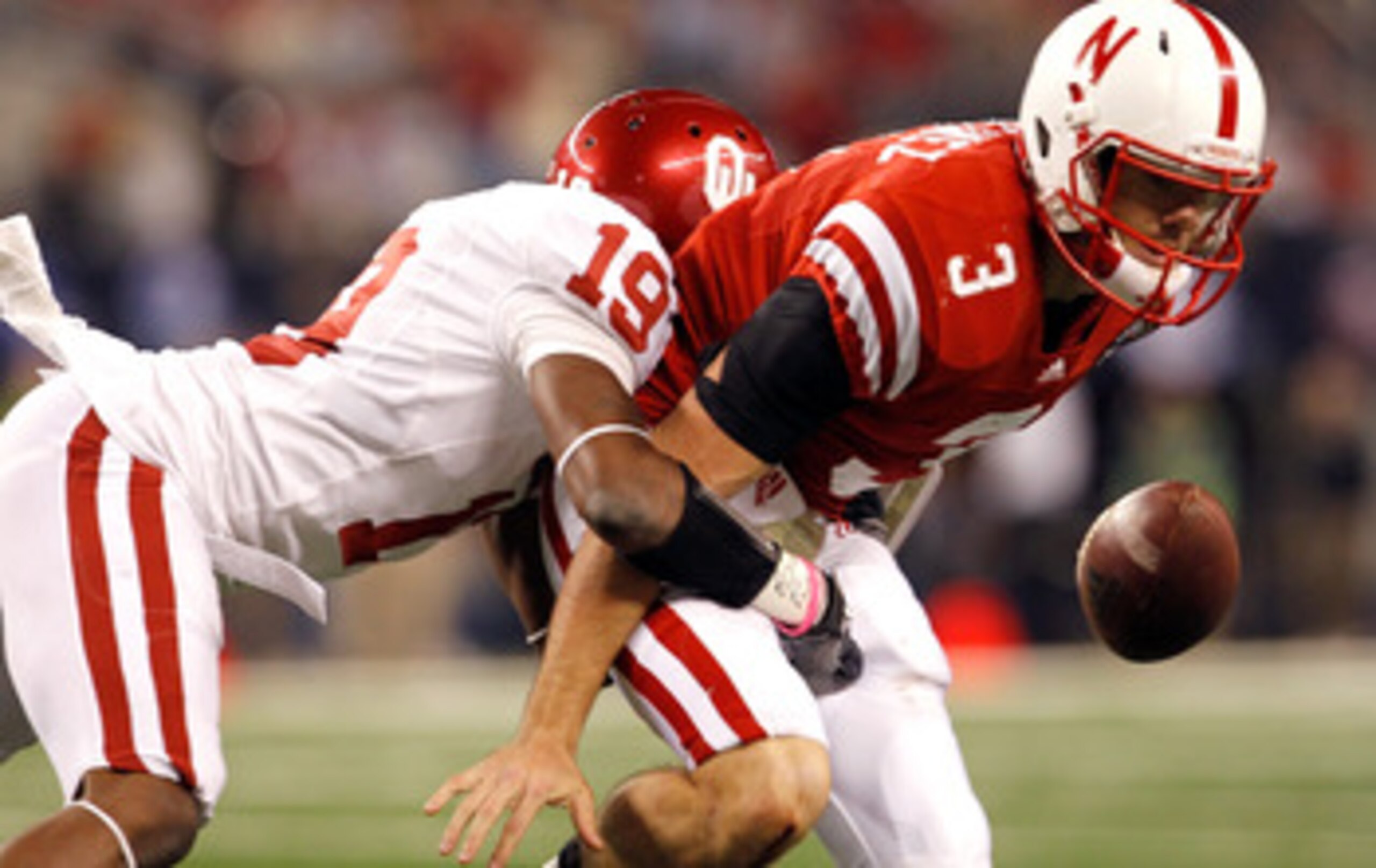 ARLINGTON, TX - DECEMBER 04:  Quarterback Taylor Martinez #3 of the Nebraska Cornhuskers fumbles the ball under pressure from defensive back Demontre Hurst #19 of the Oklahoma Sooners at Cowboys Stadium on December 4, 2010 in Arlington, Texas. The Sooners