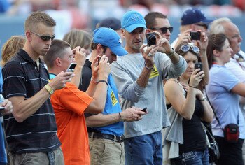 DENVER - AUGUST 21:  VIP fans on the sideline train their media capturing devices on the players during pregame warm ups as the Denver Broncos host the Detroit Lions during preseason NFL action at INVESCO Field at Mile High on August 21, 2010 in Denver, C