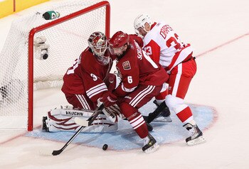 GLENDALE, AZ - APRIL 20:  David Schlemko #6 of the Phoenix Coyotes attempts to clear the puck from goaltender Ilya Bryzgalov #30 as Kris Draper #33 of the Detroit Red Wings skates in Game Four of the Western Conference Quarterfinals during the 2011 NHL St