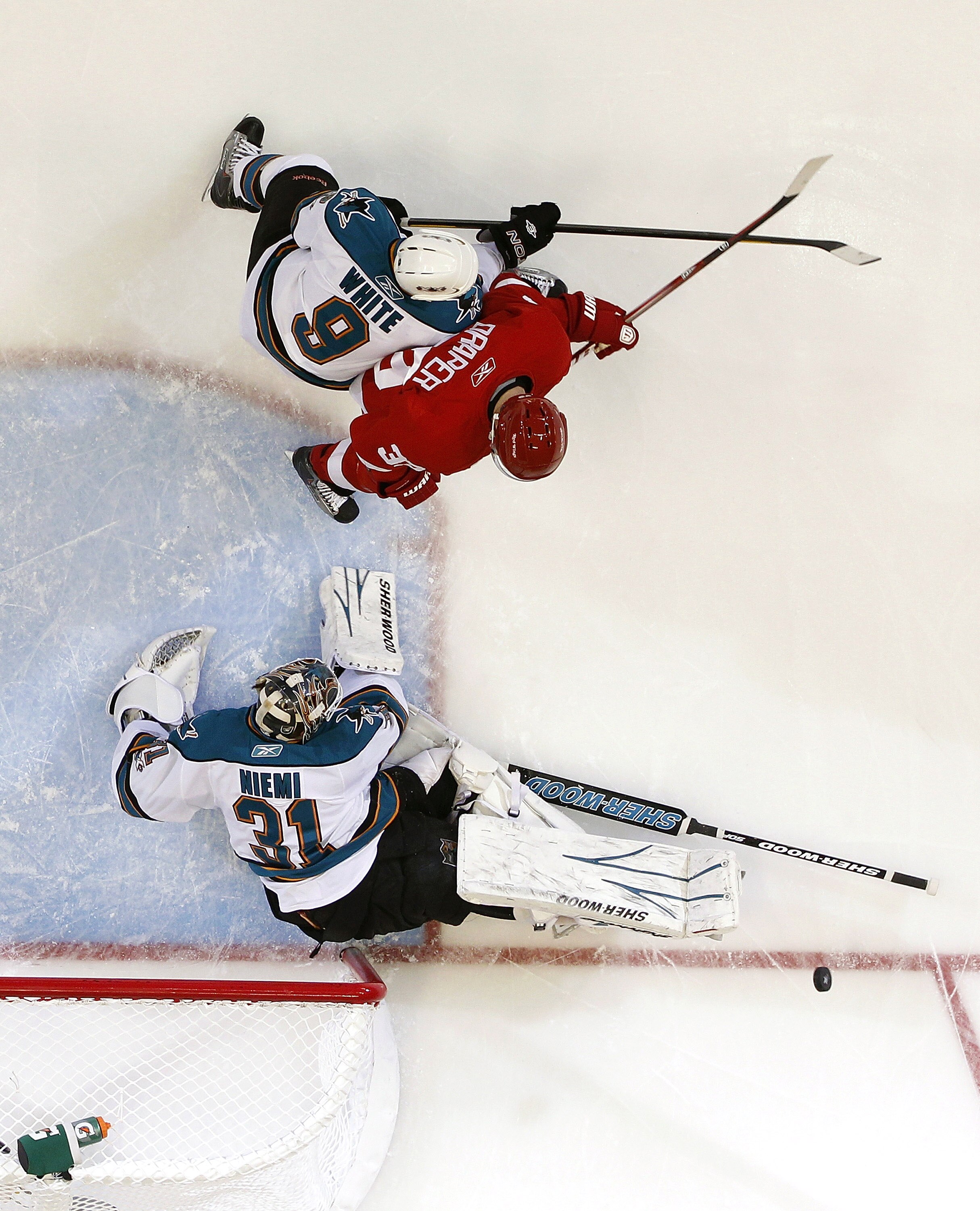 DETROIT - MAY 6: Antti Niemi #31 of the San Jose Sharks makes a save while losing his stick behind Ian White #9 and Kris Draper #33 of the Detroit Red Wings during the first period in Game Four of the Western Conference Semifinals during the 2011 NHL Stan